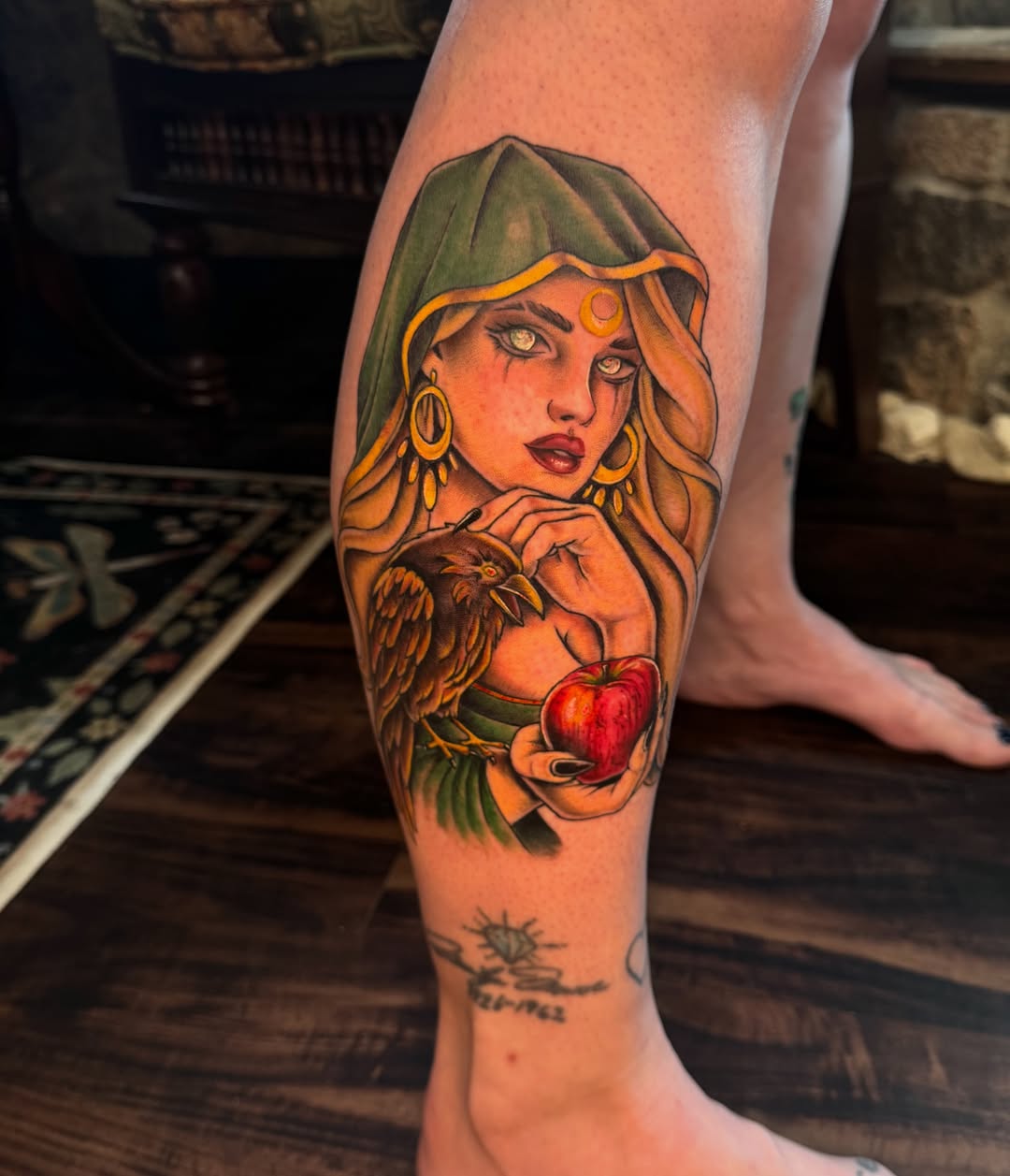 Woman with bird and apple realism tattoo on the calf by Lily Nurnberger