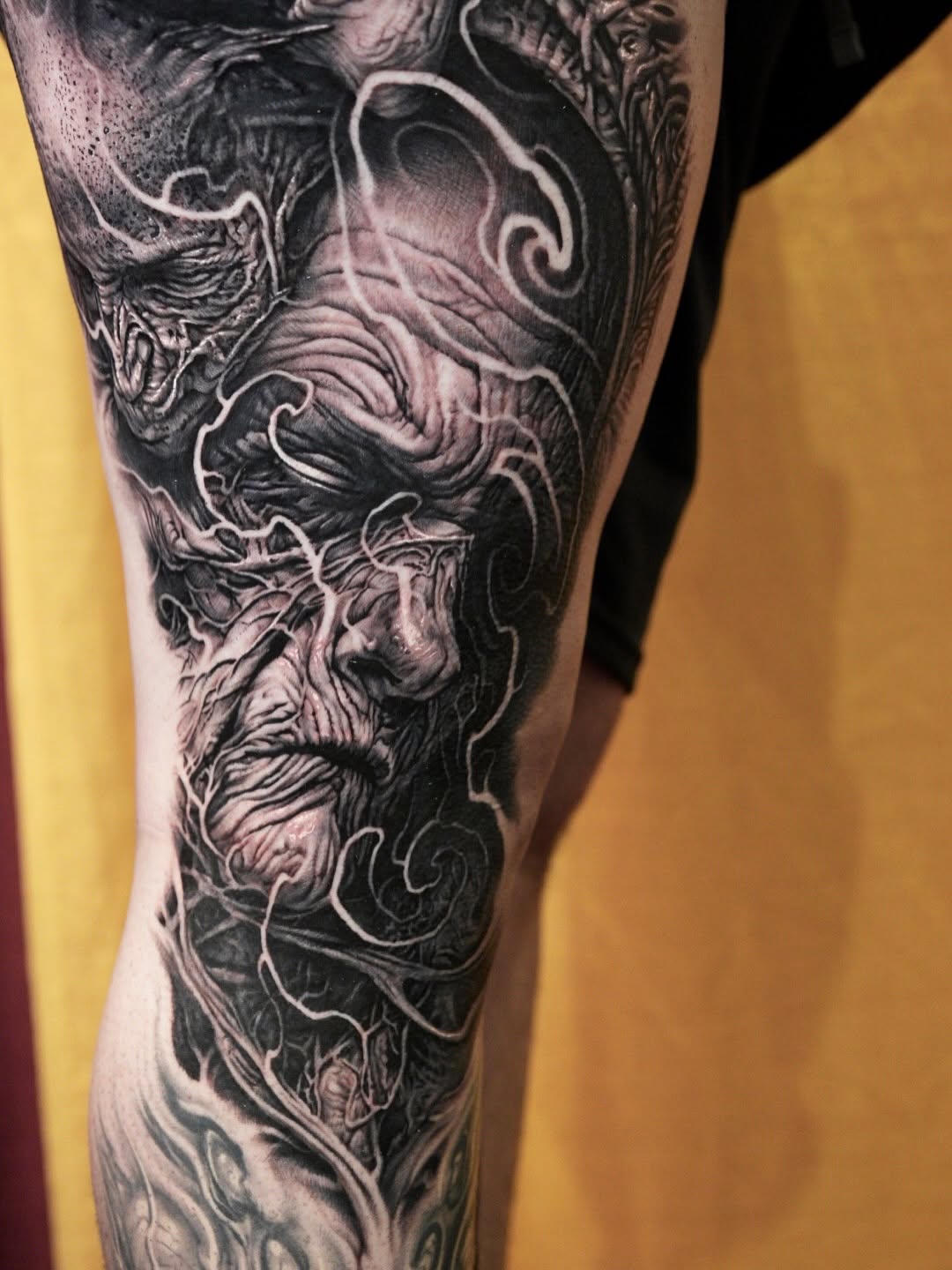 Grotesque face with swirling elements dark art tattoo on the forearm by Nico Perez