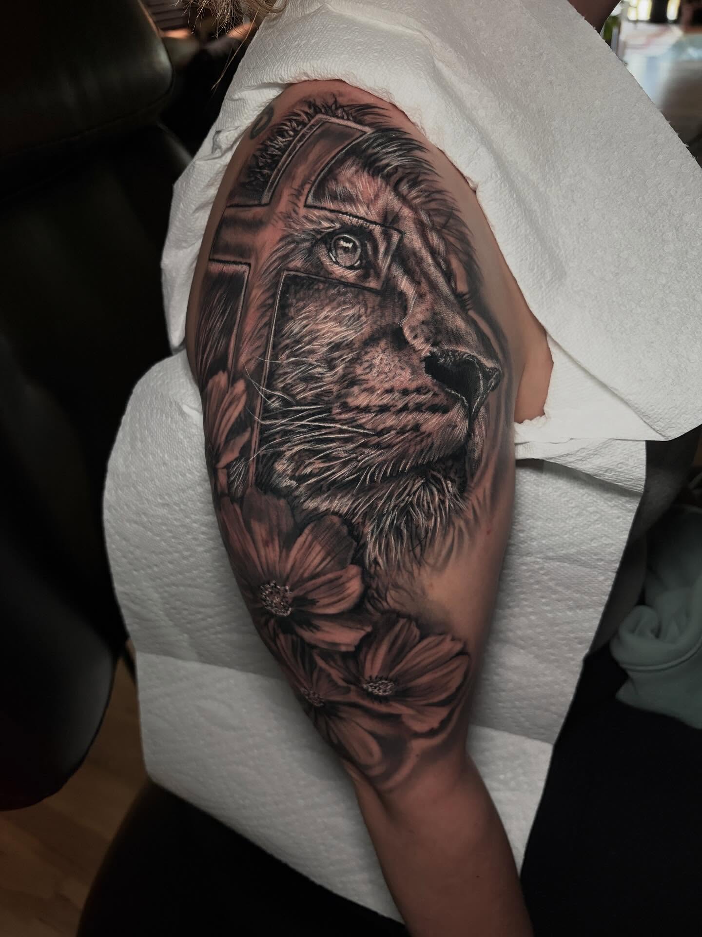 Lion and flowers realism tattoo on the forearm by Ashley Denise