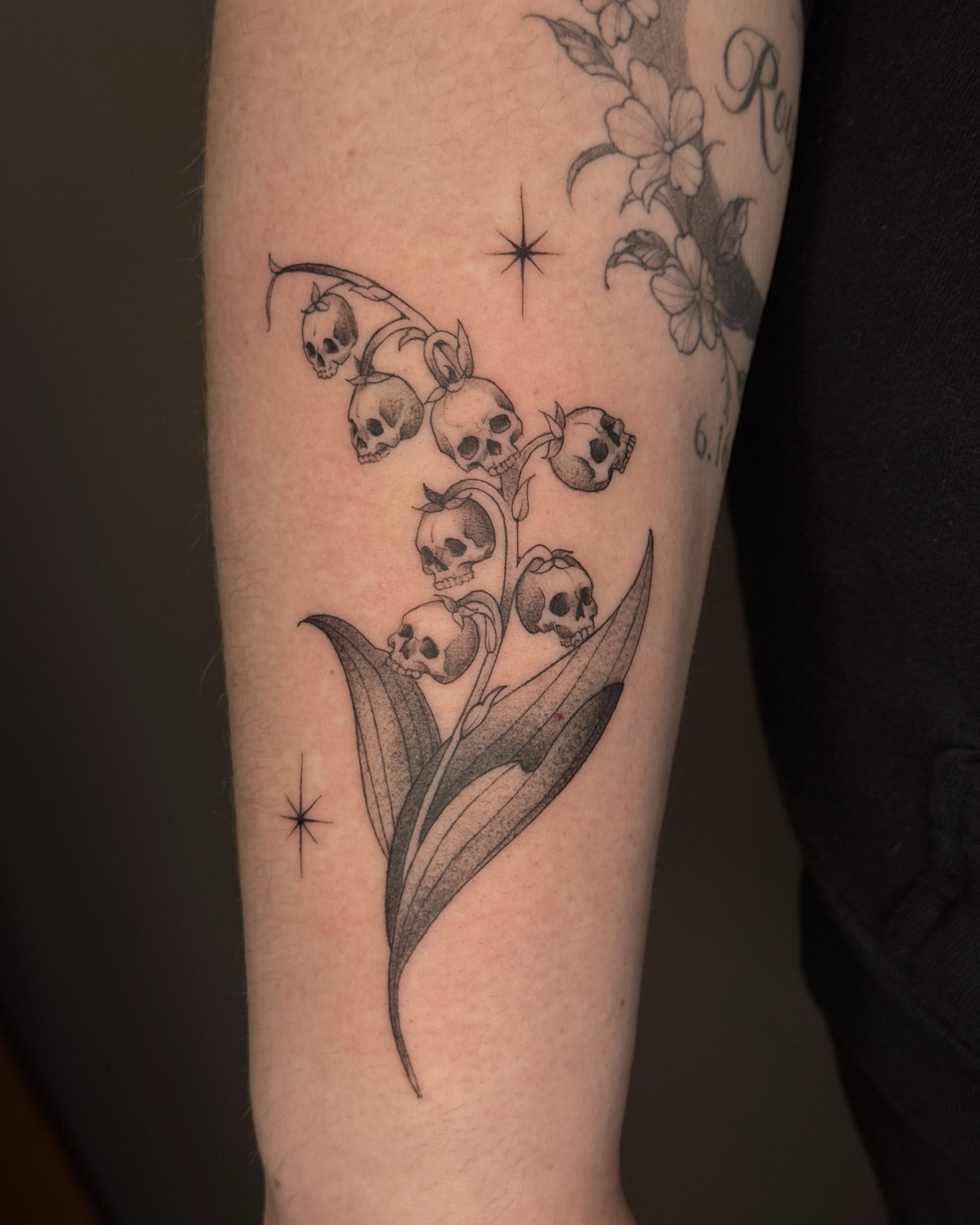 Lily of the valley skulls realism tattoo on the forearm by Suzy
