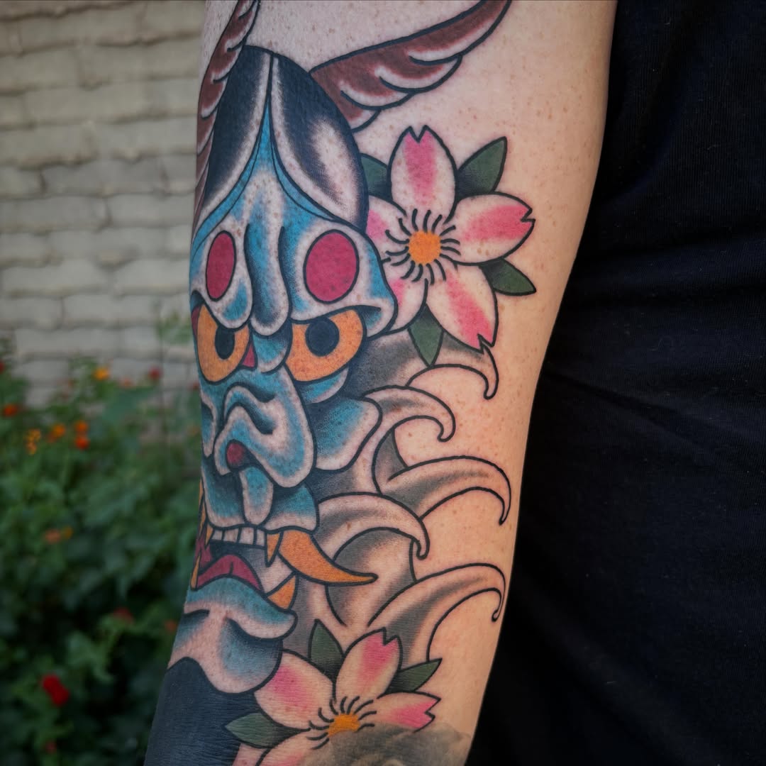 Mask and flowers American traditional tattoo on the forearm by Allyson Monique