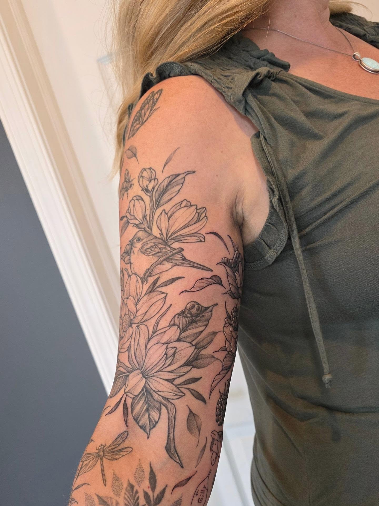 Floral and bird realism tattoo on the upper arm by Dani Bond