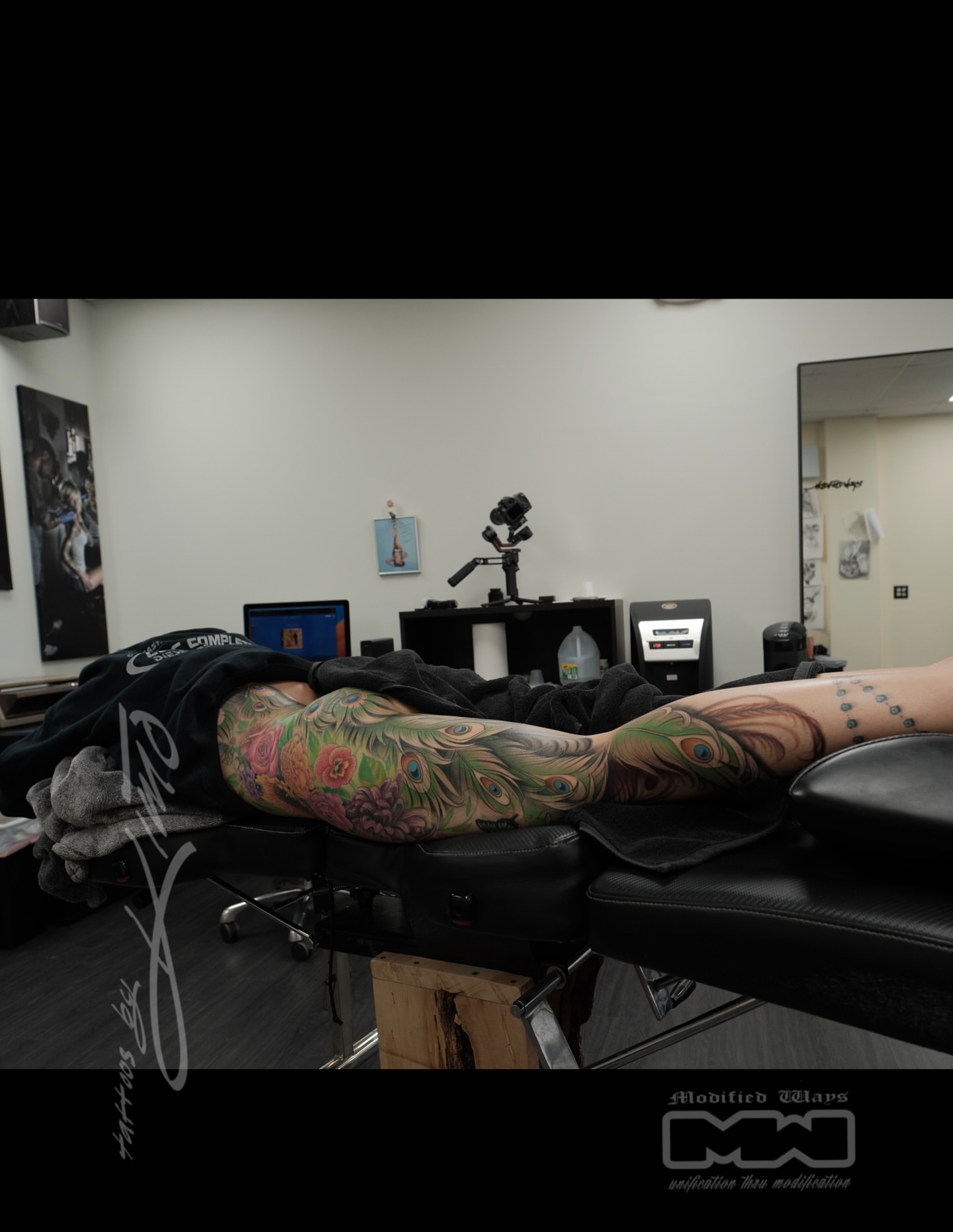 Peacock feathers neo-traditional tattoo on the upper arm by Kansas City tattoo artist