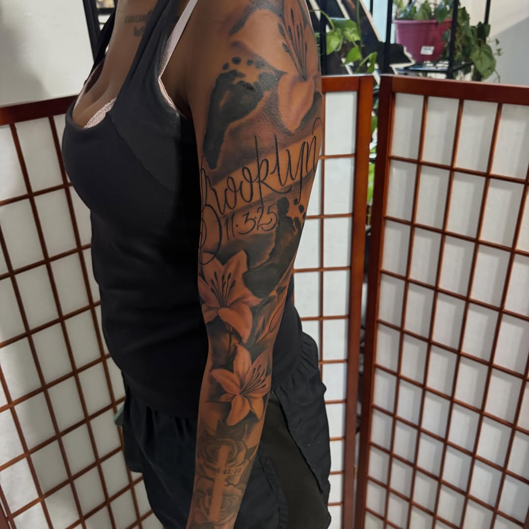 Lily and script black and grey tattoo on the forearm by D. Davis
