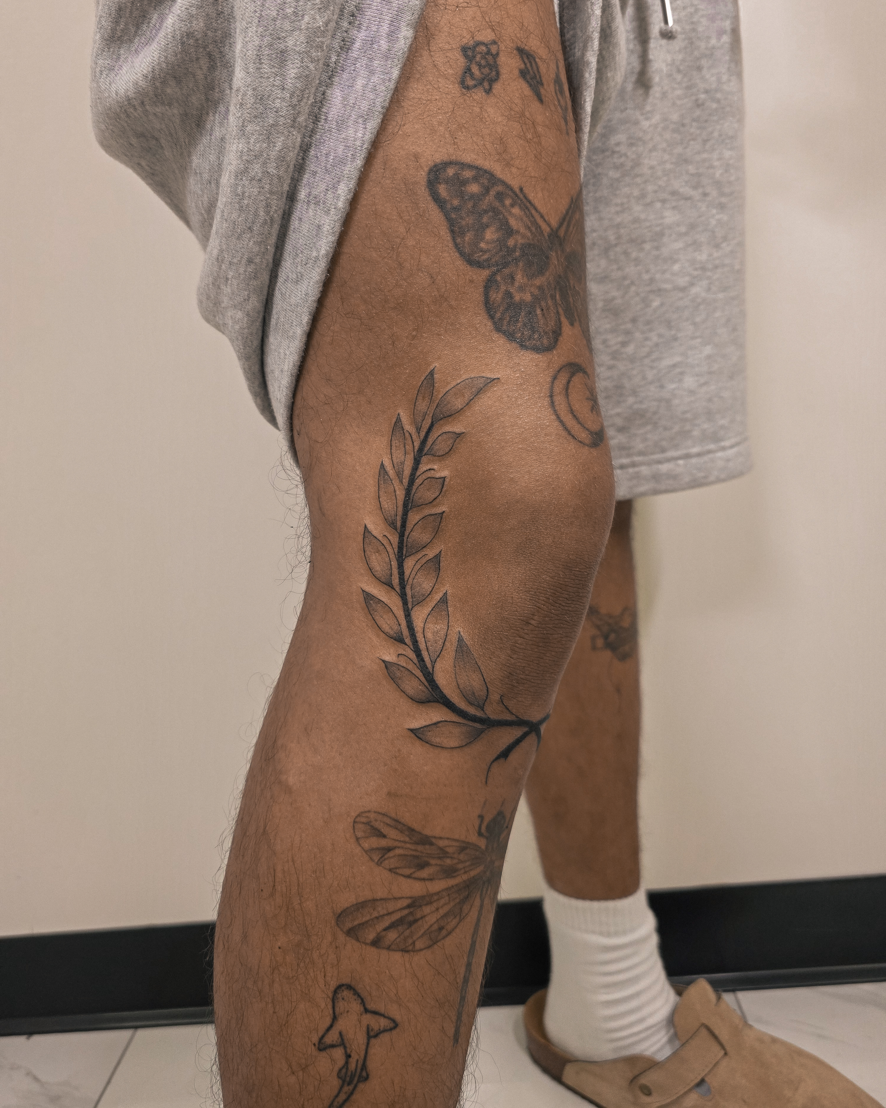 Wreath and dragonfly black and grey tattoo on the thigh by Richmond tattoo shop, Richmond, Texas