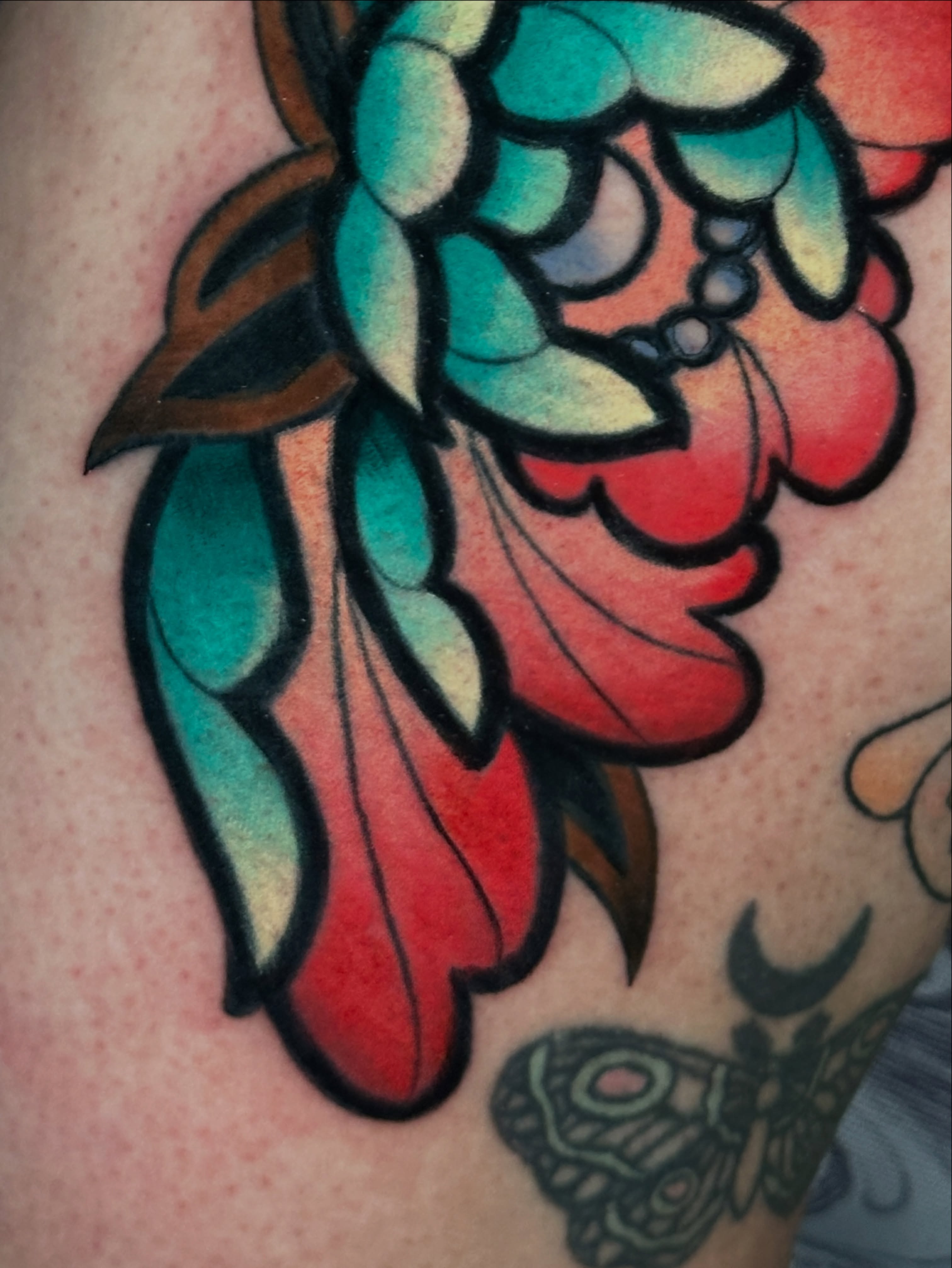 Floral mask American traditional tattoo on the upper arm by Dustin Hughes