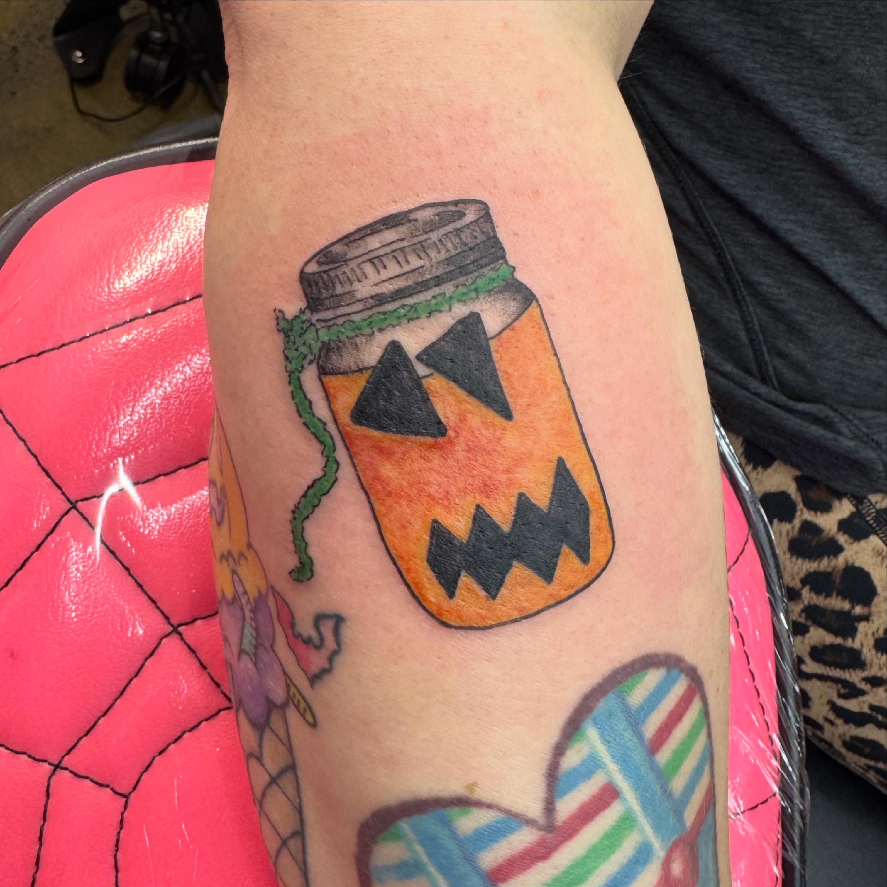 Jack-o'-lantern in jar American traditional tattoo on the forearm by Jada Reynolds