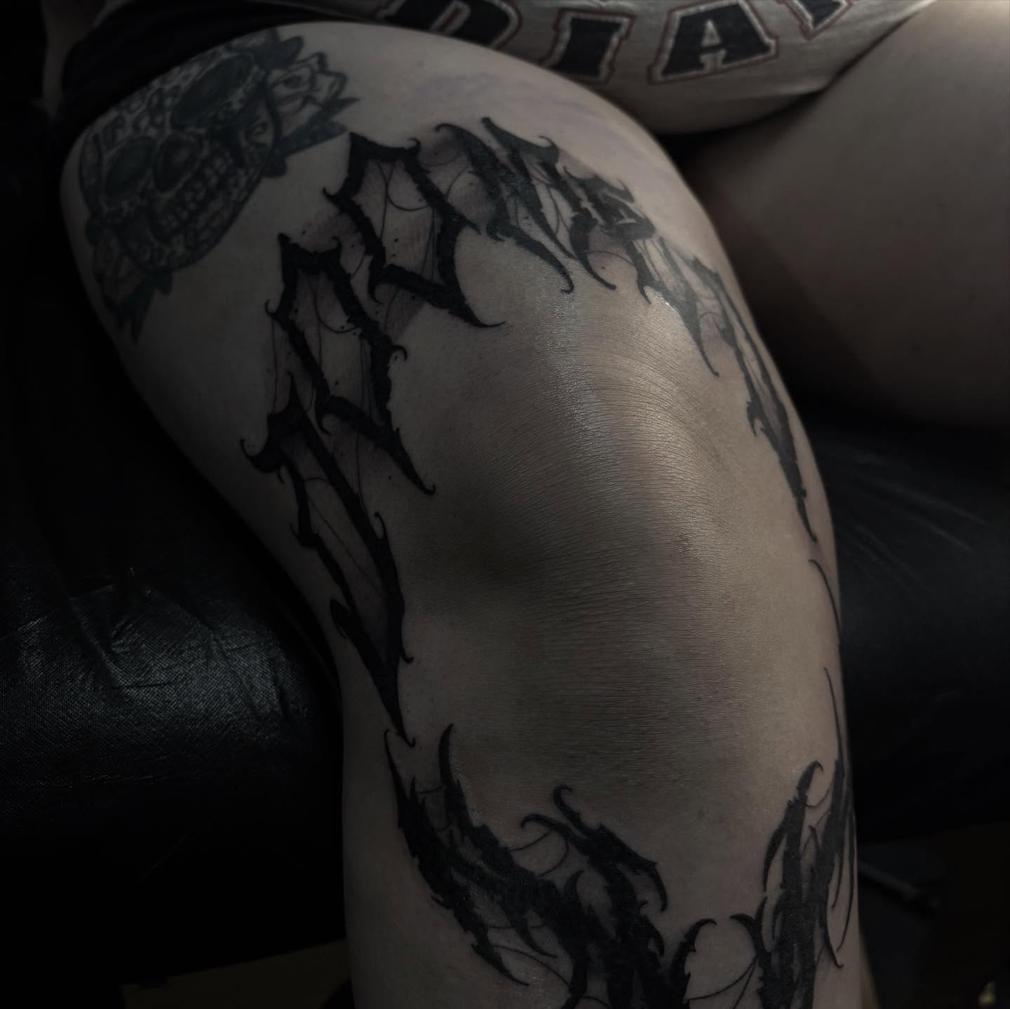 Gothic script black and grey tattoo on the thigh by suzie