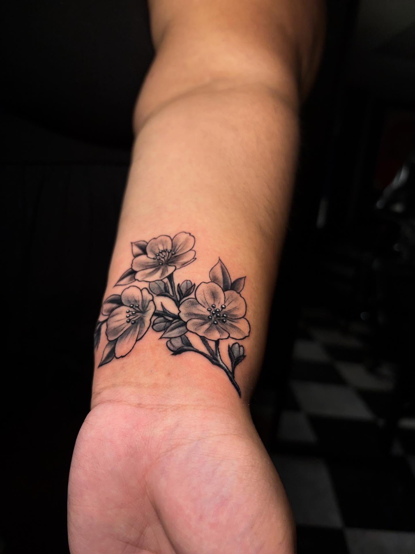Flowers black and grey tattoo on the forearm by Nikko
