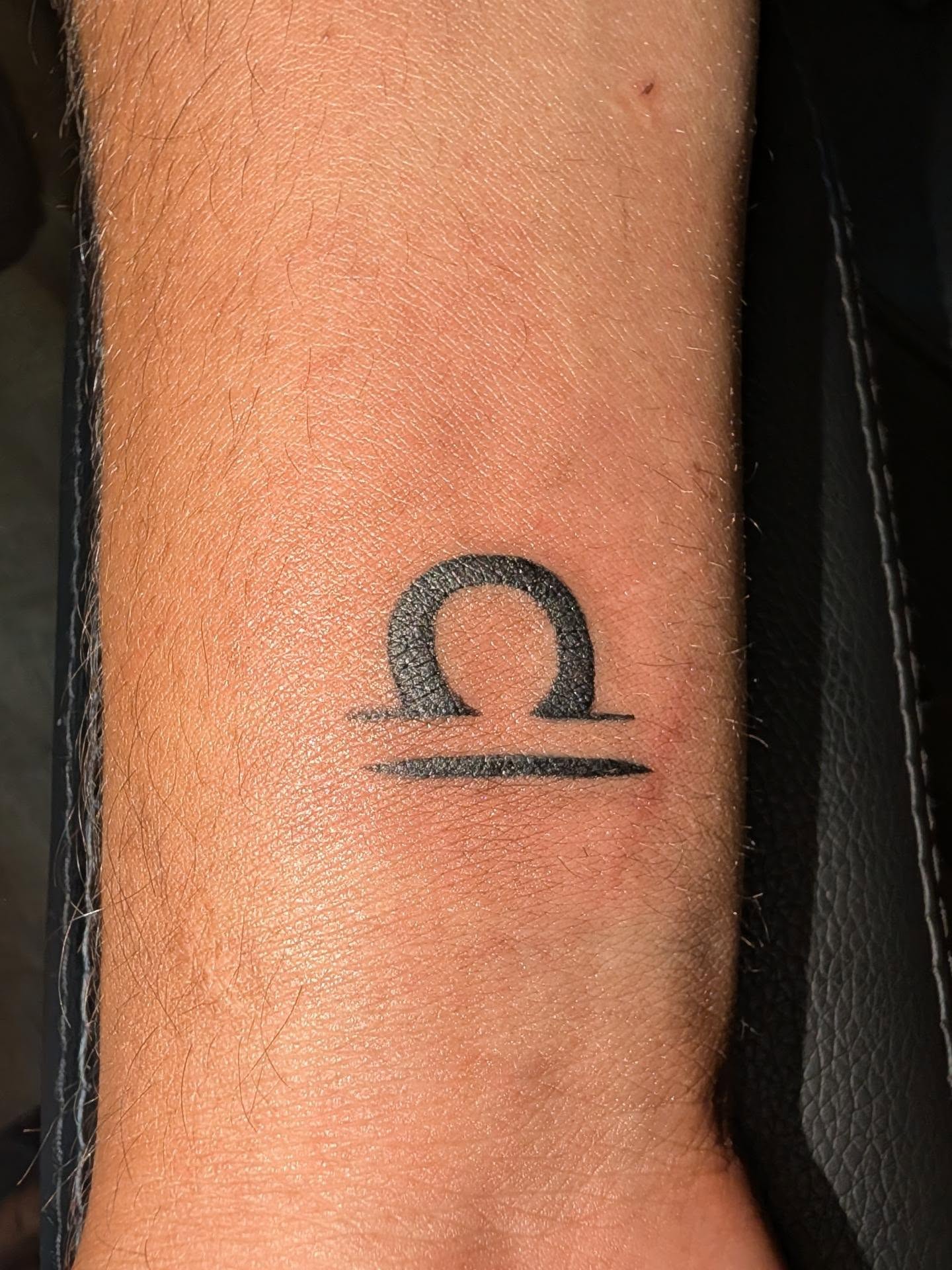 Libra symbol black and grey tattoo on the forearm by Tony