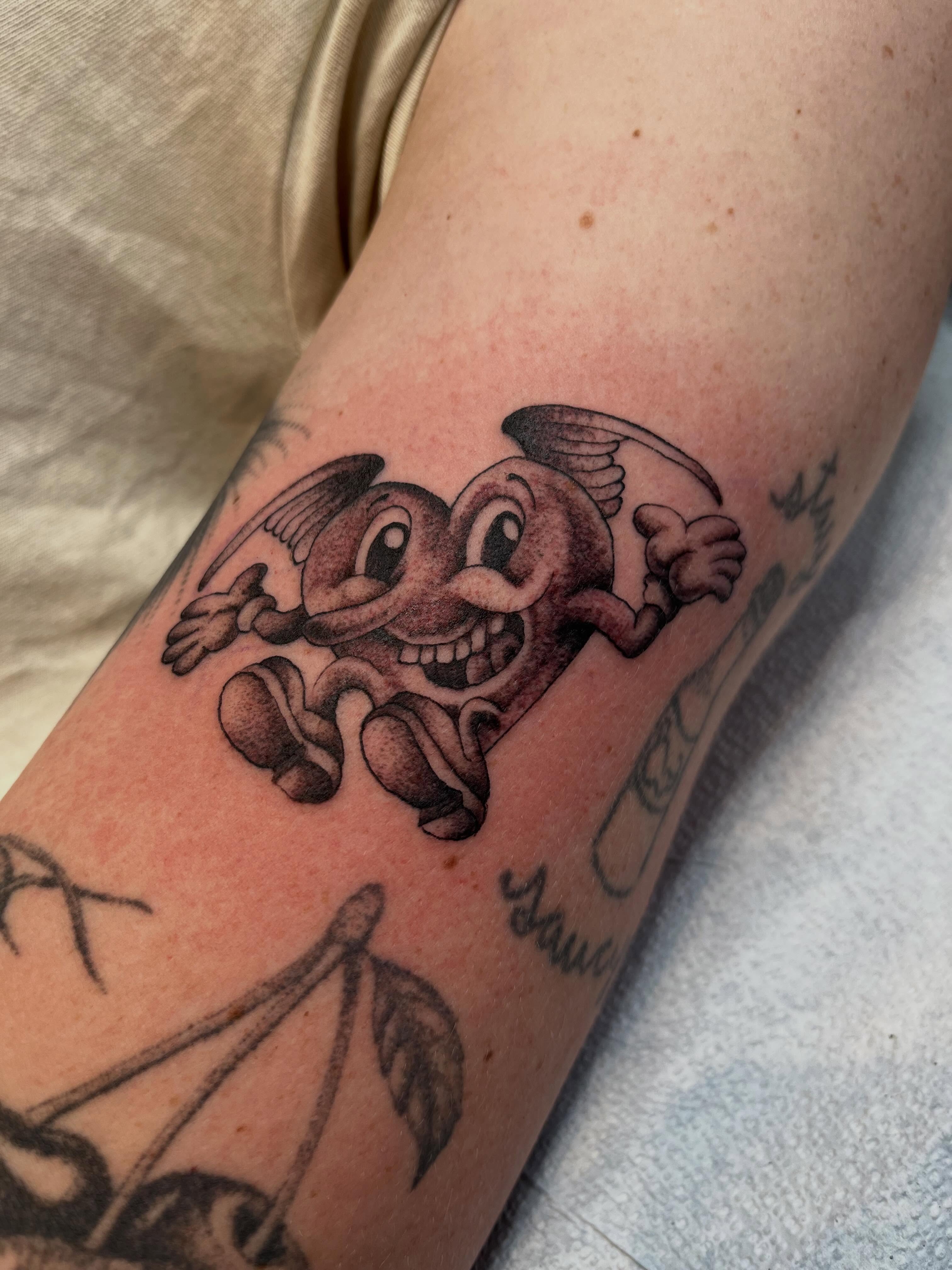 Smiling devil character black and grey tattoo on the forearm by Chris Kline