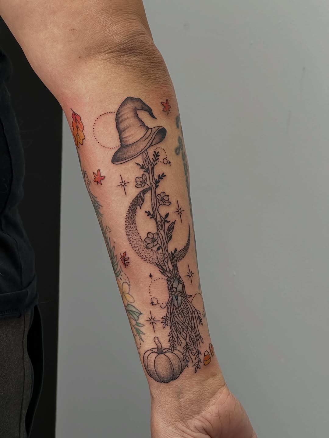 Witch hat with moon and pumpkin minimalist tattoo on the forearm by Mandy Kaur