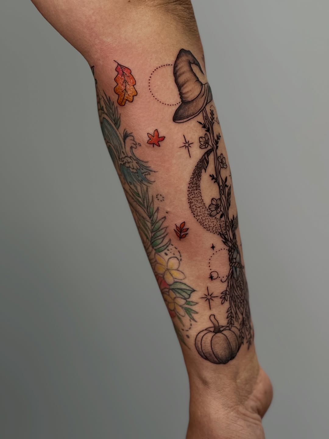 Witch hat, moon, pumpkin, leaves, flowers ornamental tattoo on the forearm by Mandy Kaur