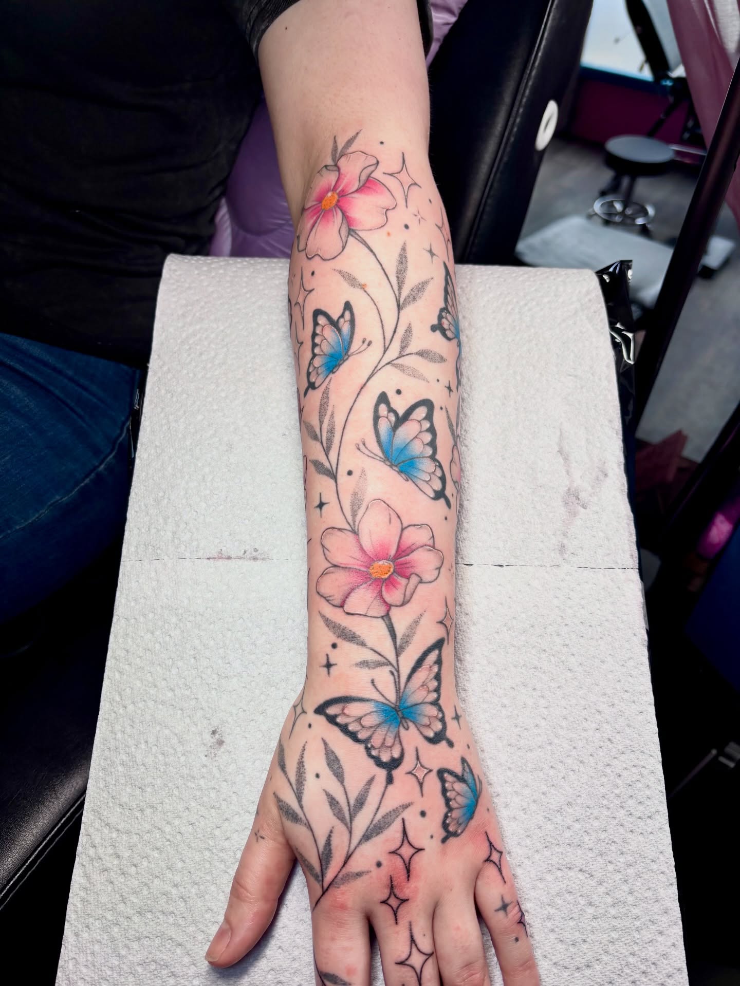 Flowers and butterflies new school tattoo on the forearm by Charlotte Brown, Leeds, England