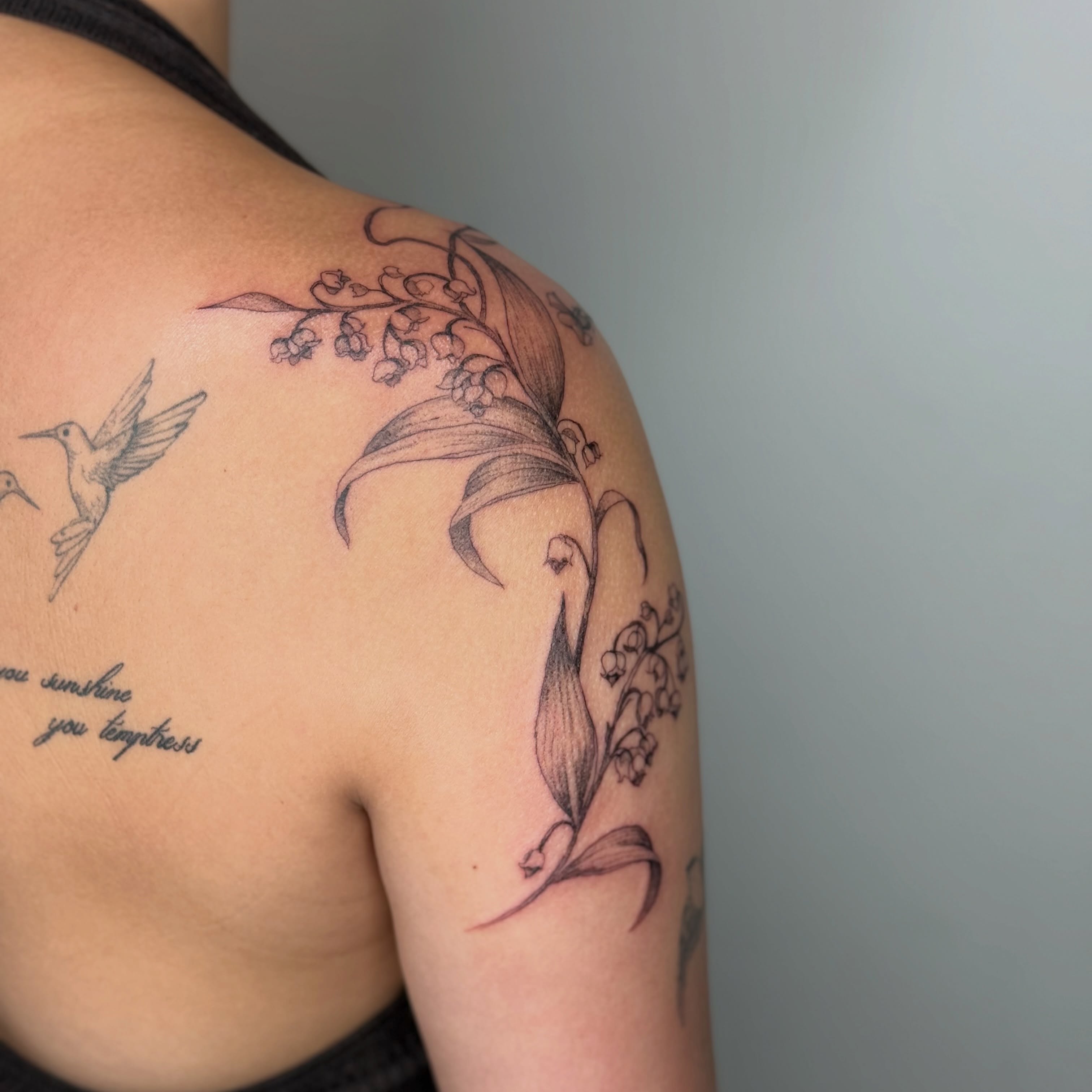 Lily of the valley and hummingbird black and grey tattoo on the shoulder by ❁ Marlo Marquise Tattoo Artist ❁