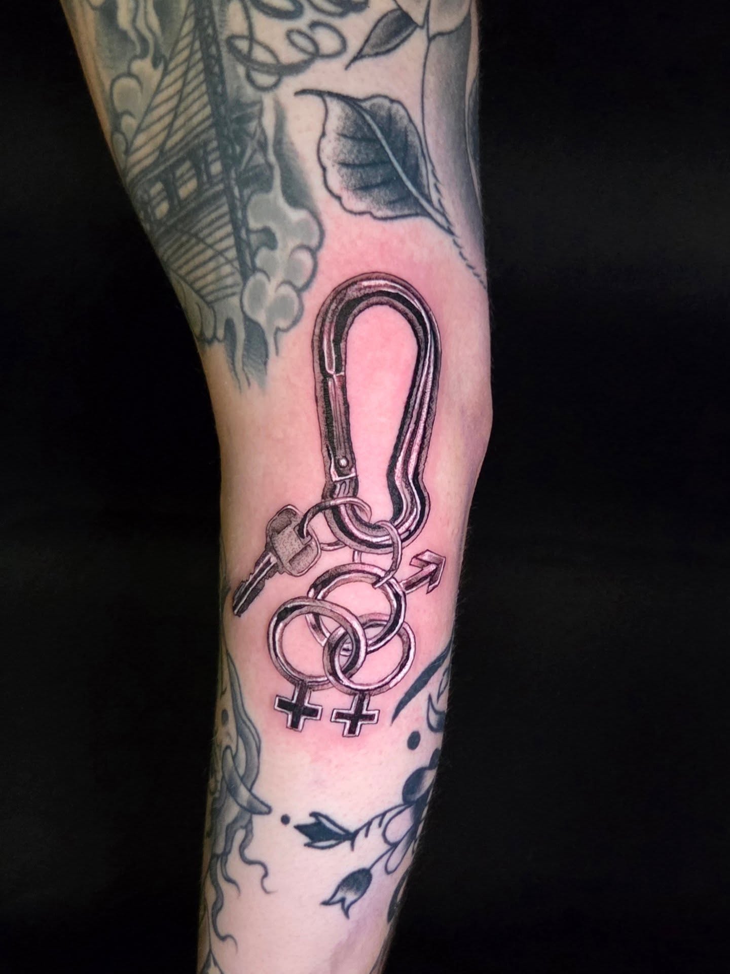 Carabiner and gender symbols black and grey tattoo on the forearm by Maya Neideck