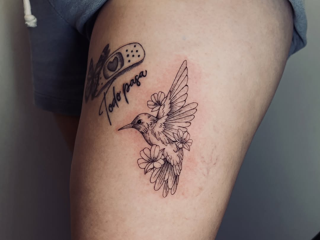 Hummingbird with flowers and band-aid fine line tattoo on the thigh by vivian