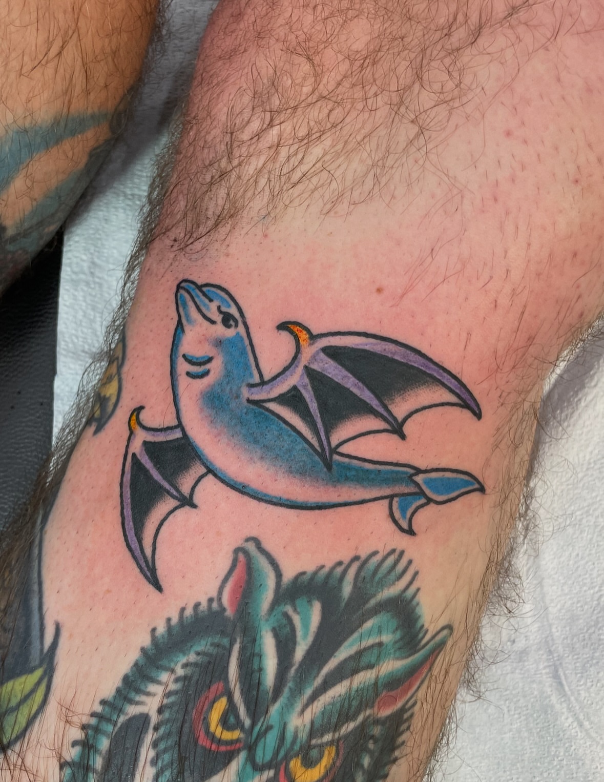 Dolphin with wings American traditional tattoo on the forearm by Greg De Hoot, Youngsville, North Carolina