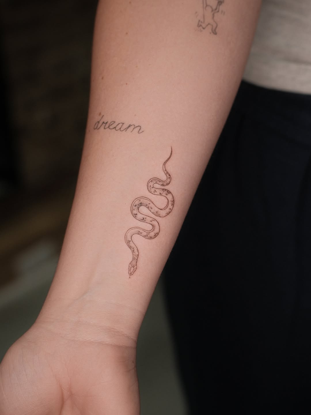 Snake and script minimalist tattoo on the forearm by Valerie