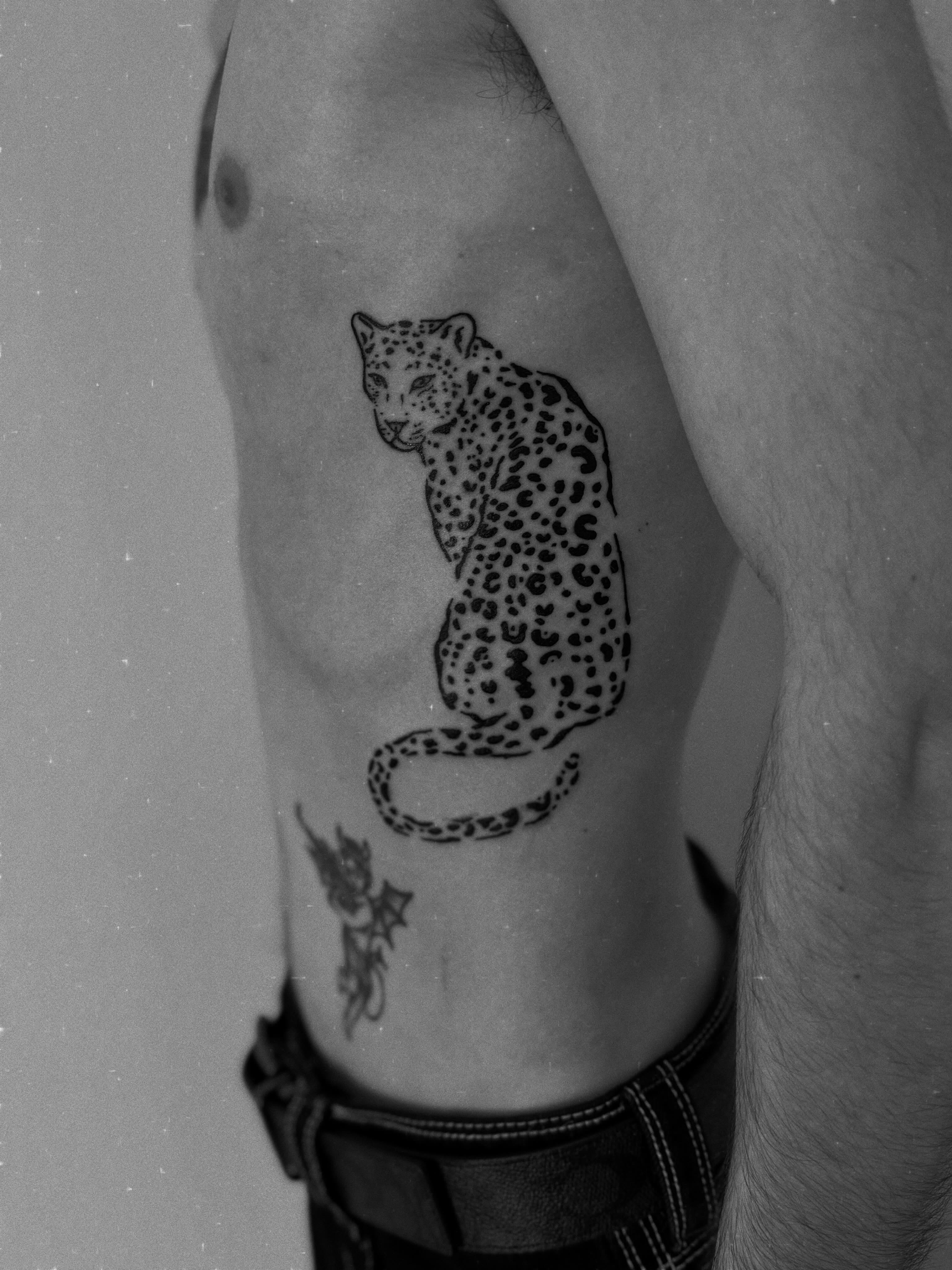 Snow leopard black and grey tattoo on the ribs by Jessica Abbey