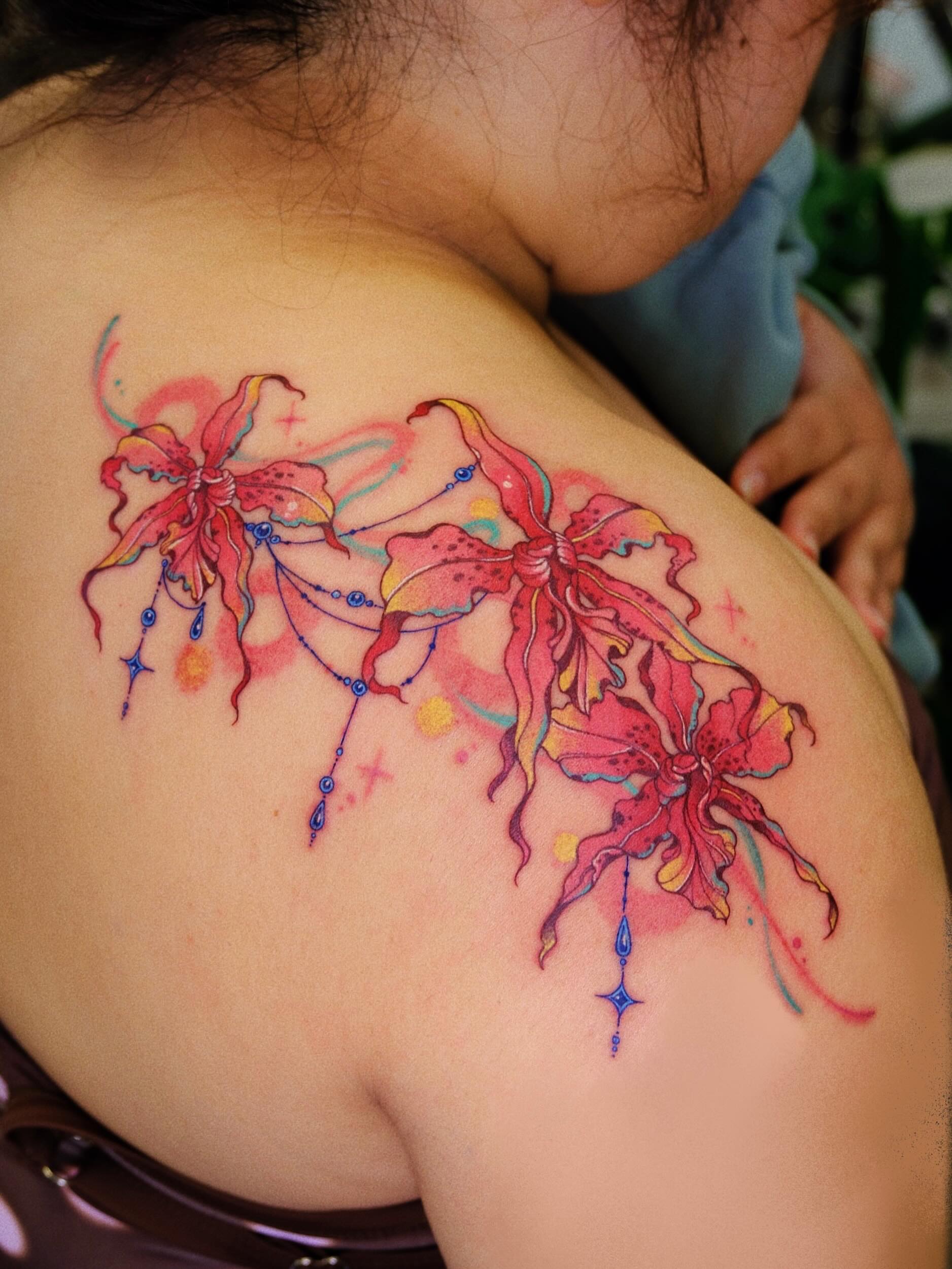 Lilies watercolor tattoo on the shoulder by rita_tattooist