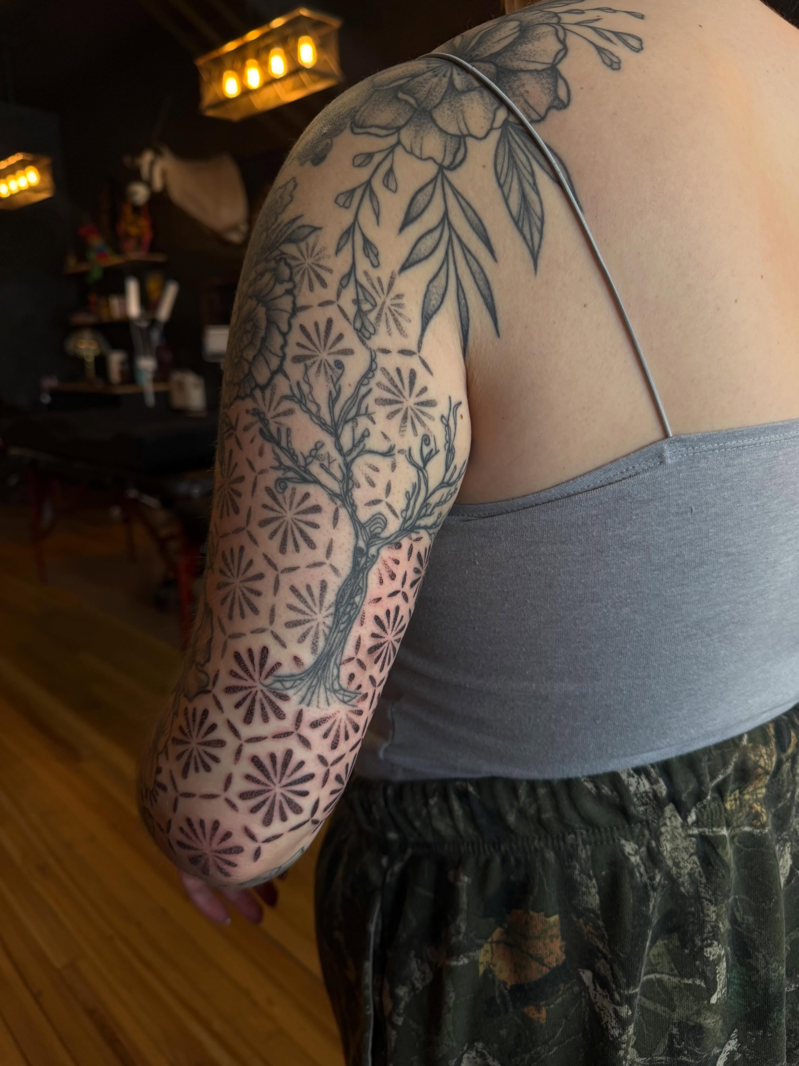 Tree and floral patterns dotwork tattoo on the upper arm by Allison