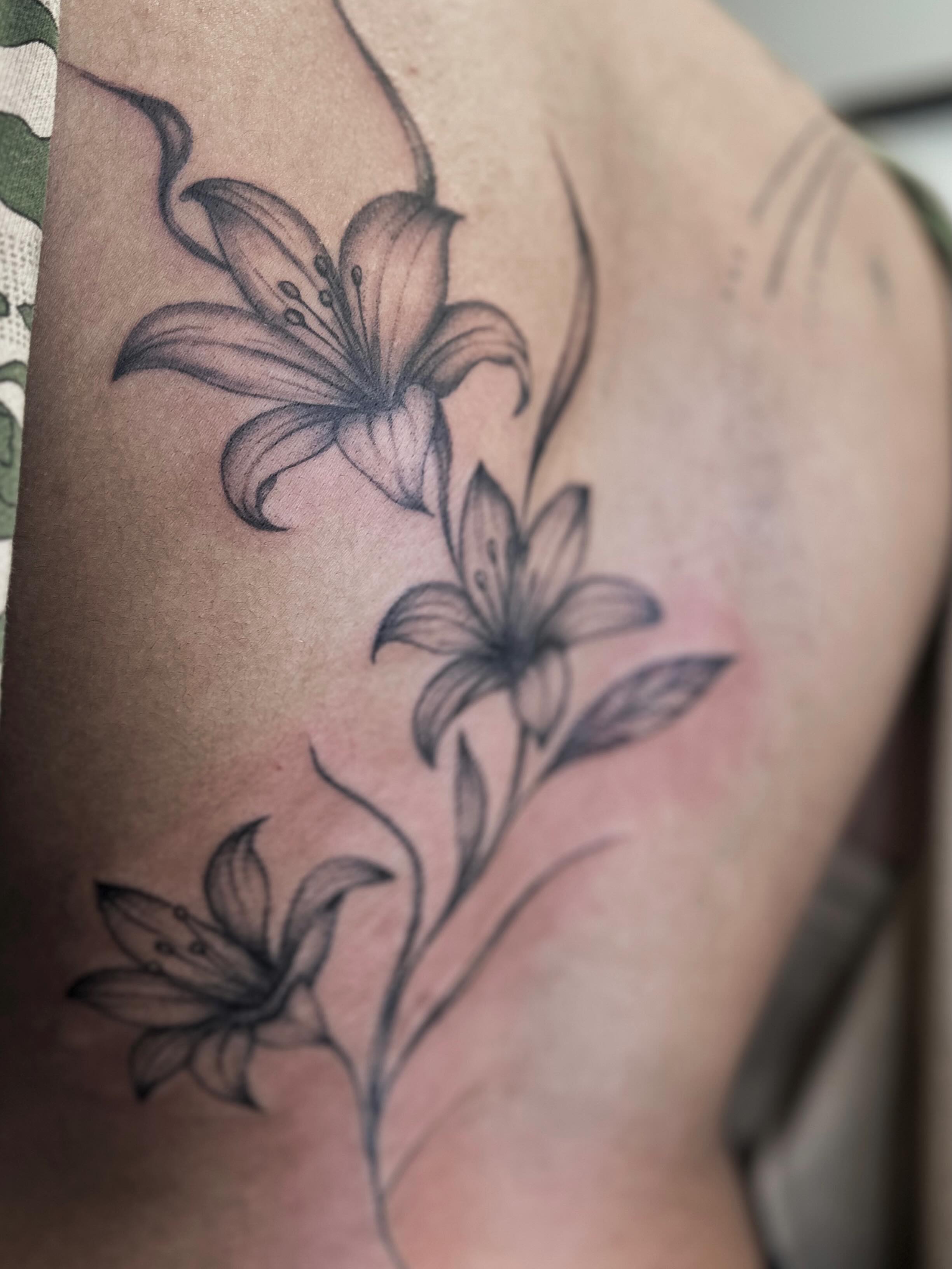 Lily black and grey tattoo on the upper arm by kenna