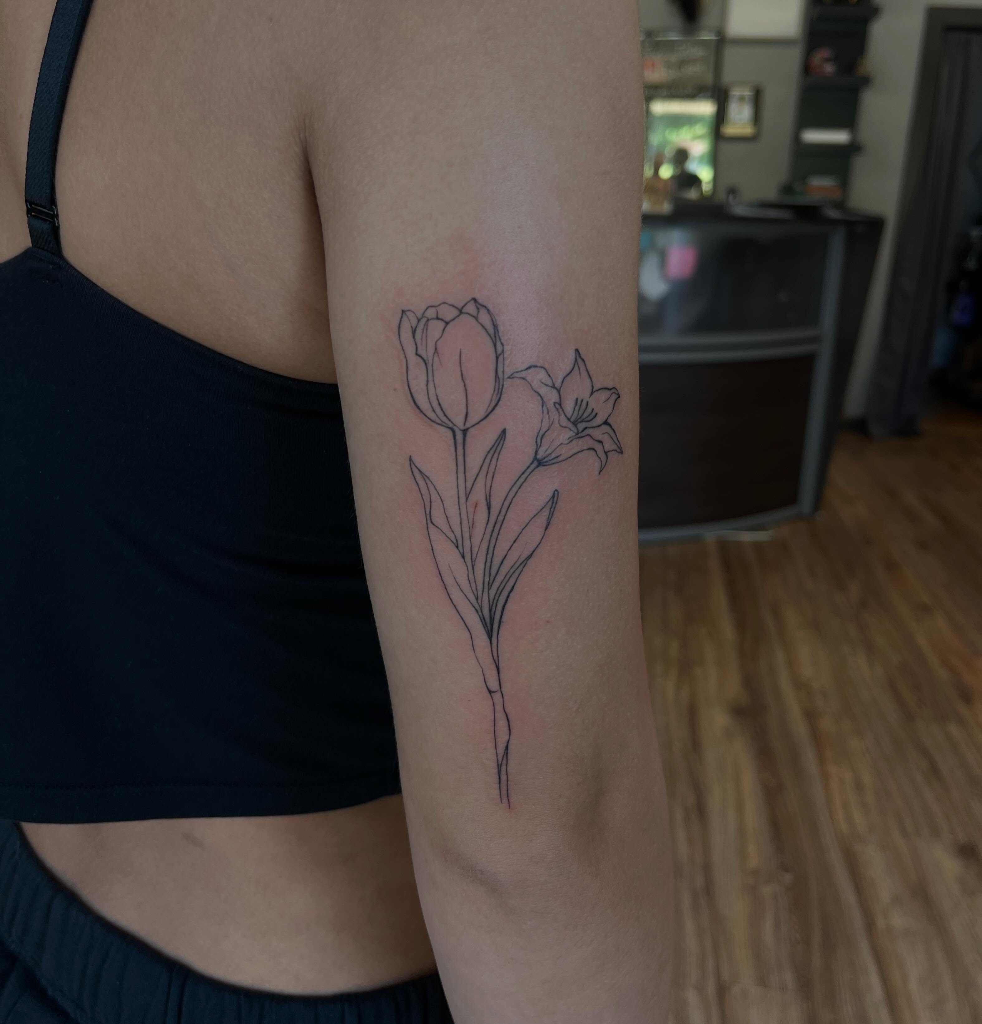 Tulip and lily fine line tattoo on the forearm by Cass