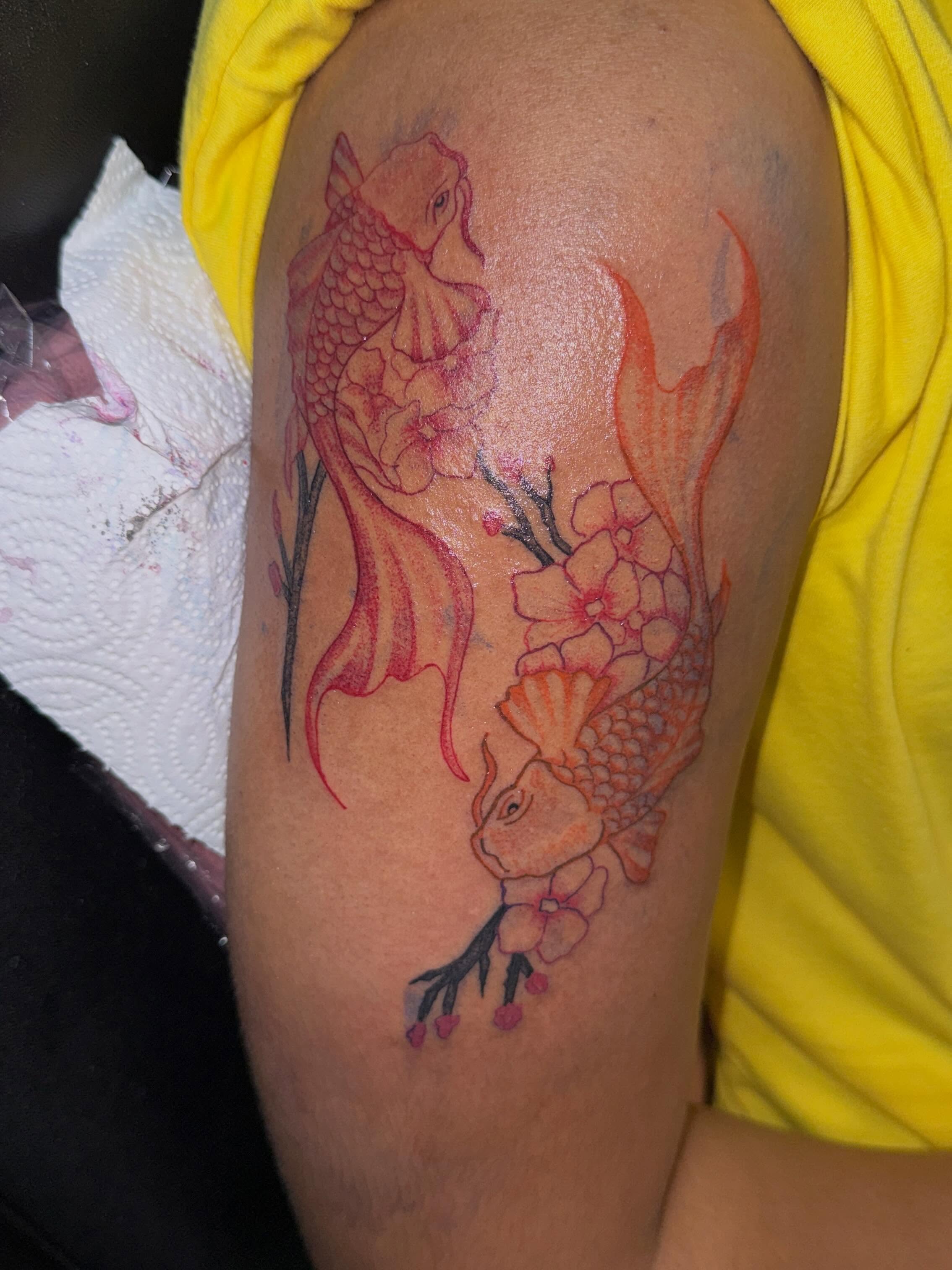 Koi fish and cherry blossoms watercolor tattoo on the upper arm by Destini