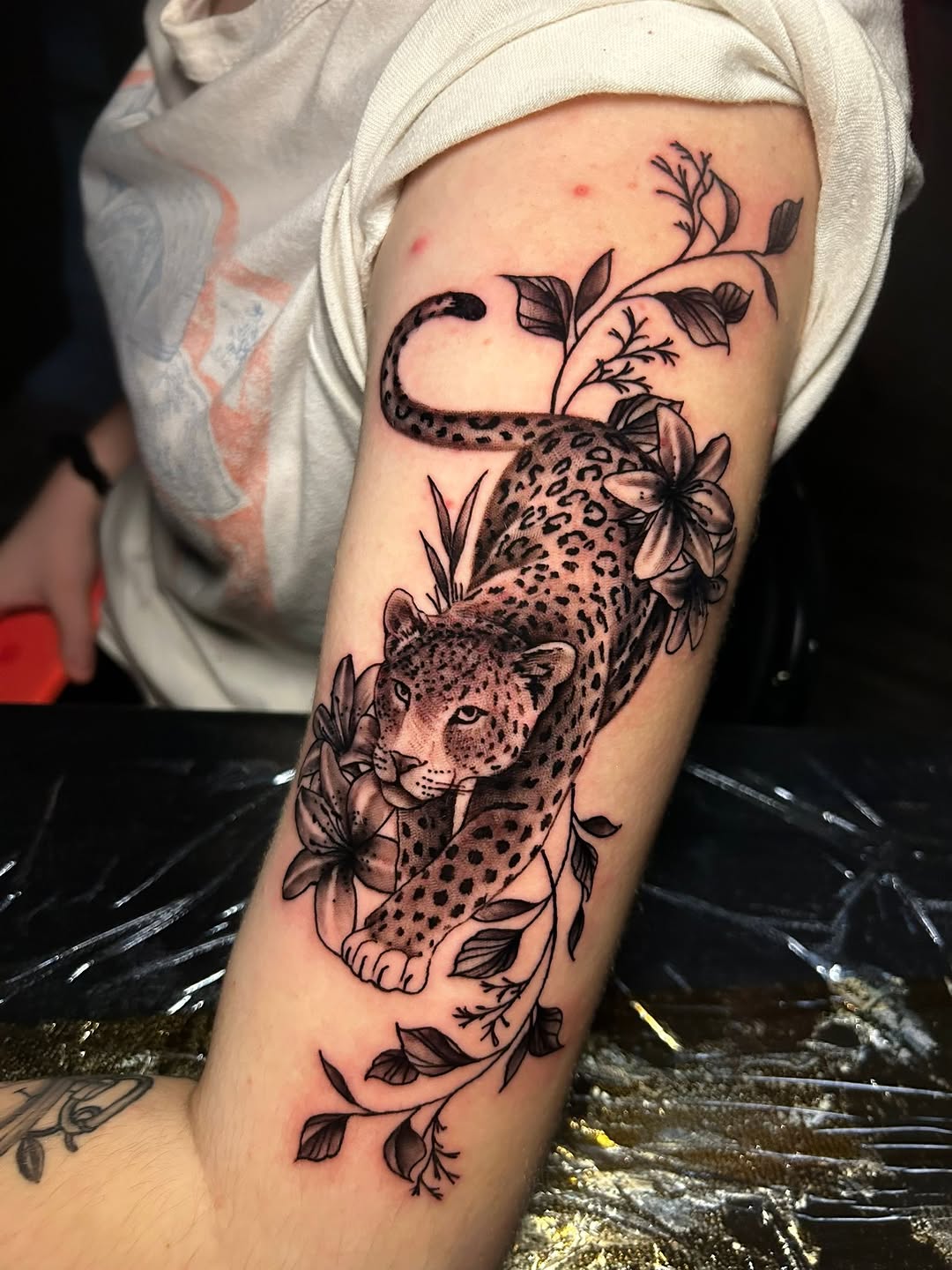 Leopard with flowers realism tattoo on the forearm by Ferlandis Fitch, Long Beach, California