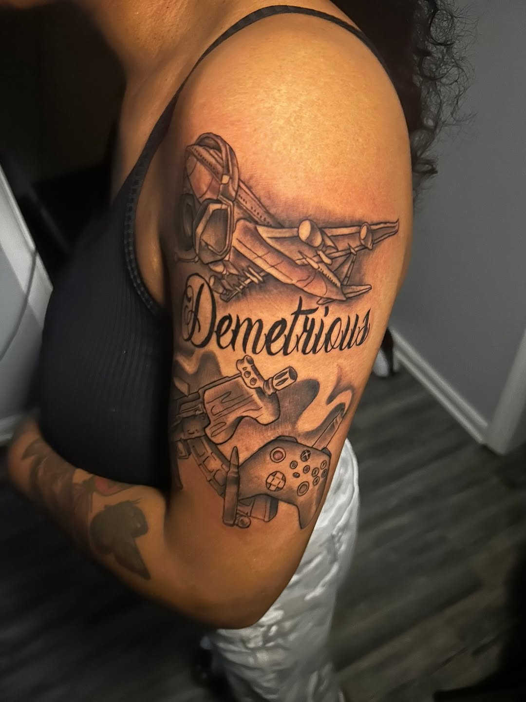 Airplane, gun, video game controller, name lettering tattoo on the shoulder by Ferlandis Fitch, Long Beach, California