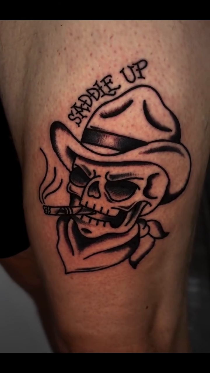 Skull in cowboy hat with cigar realism tattoo on the upper arm by Jenna Clayton