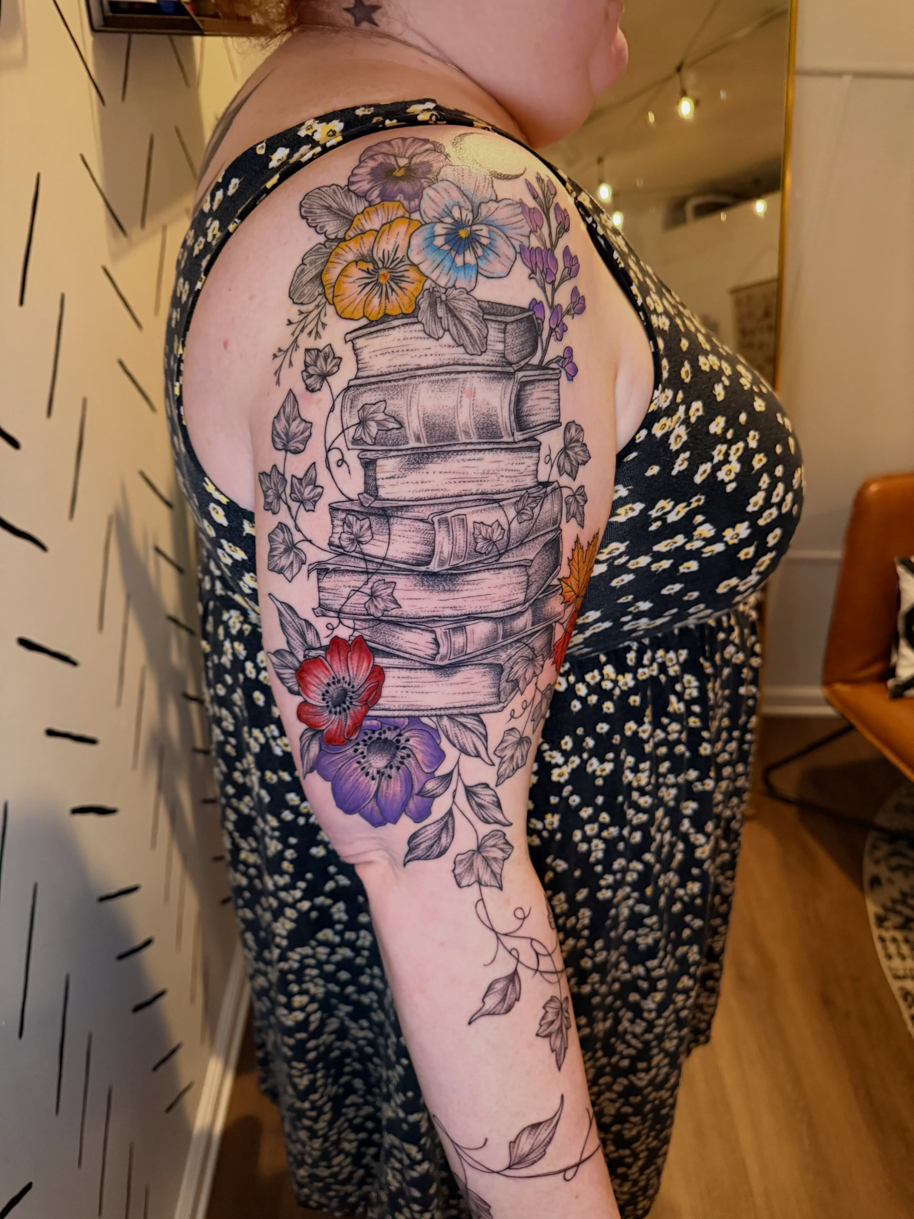 Stacked books and floral arrangement dotwork tattoo on the forearm by ππ£ππ€π₯π ππ¦ππ‘π, Lakewood, Colorado