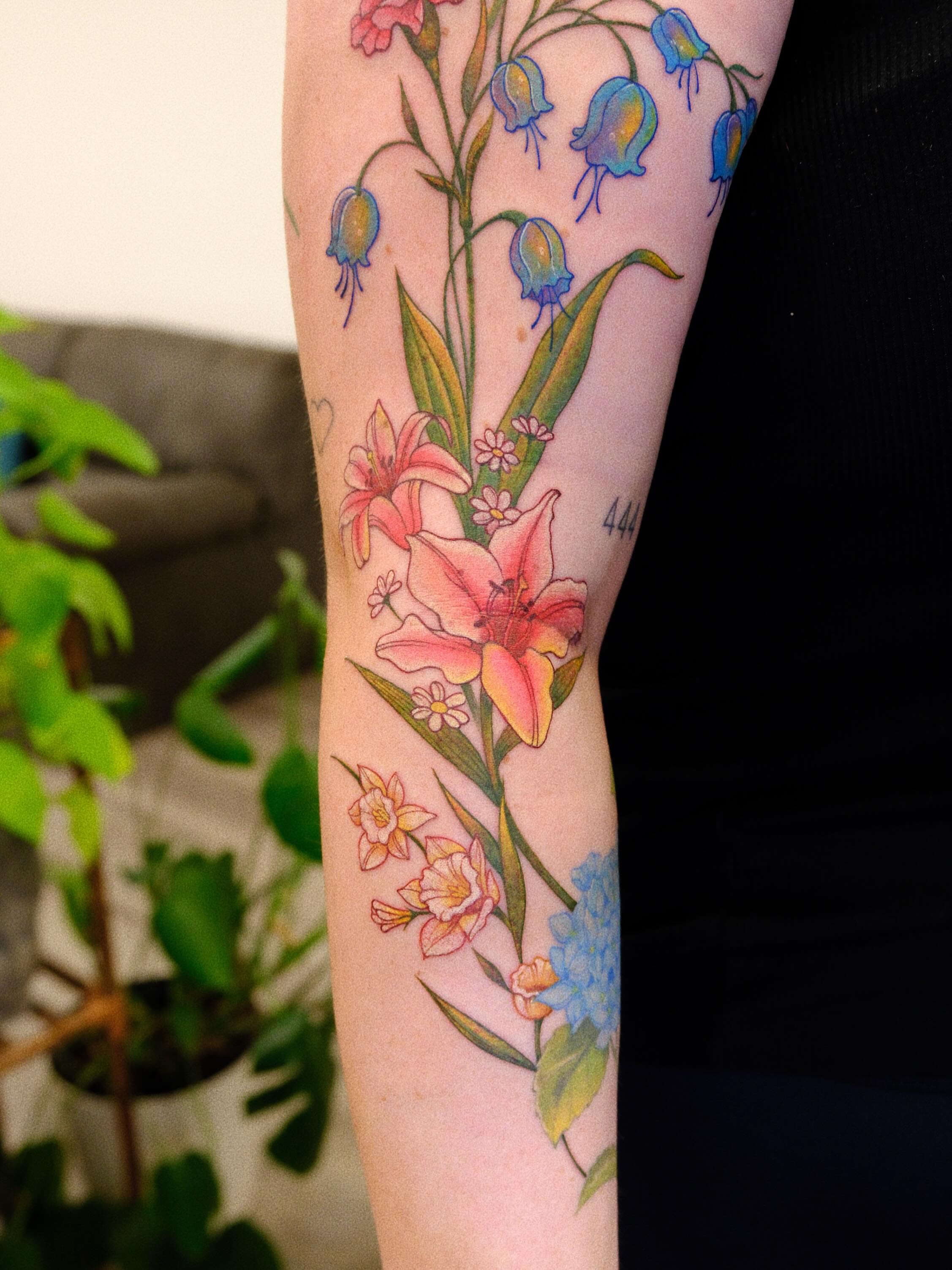 Lilies and bluebells watercolor tattoo on the forearm by rita_tattooist