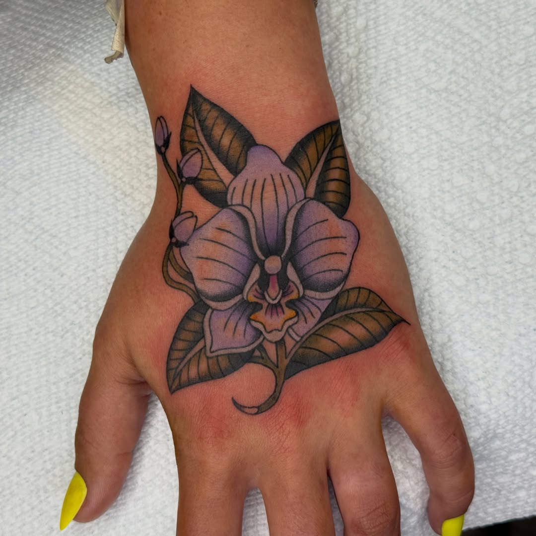 Orchid American traditional tattoo on the hand by Allie Barringer