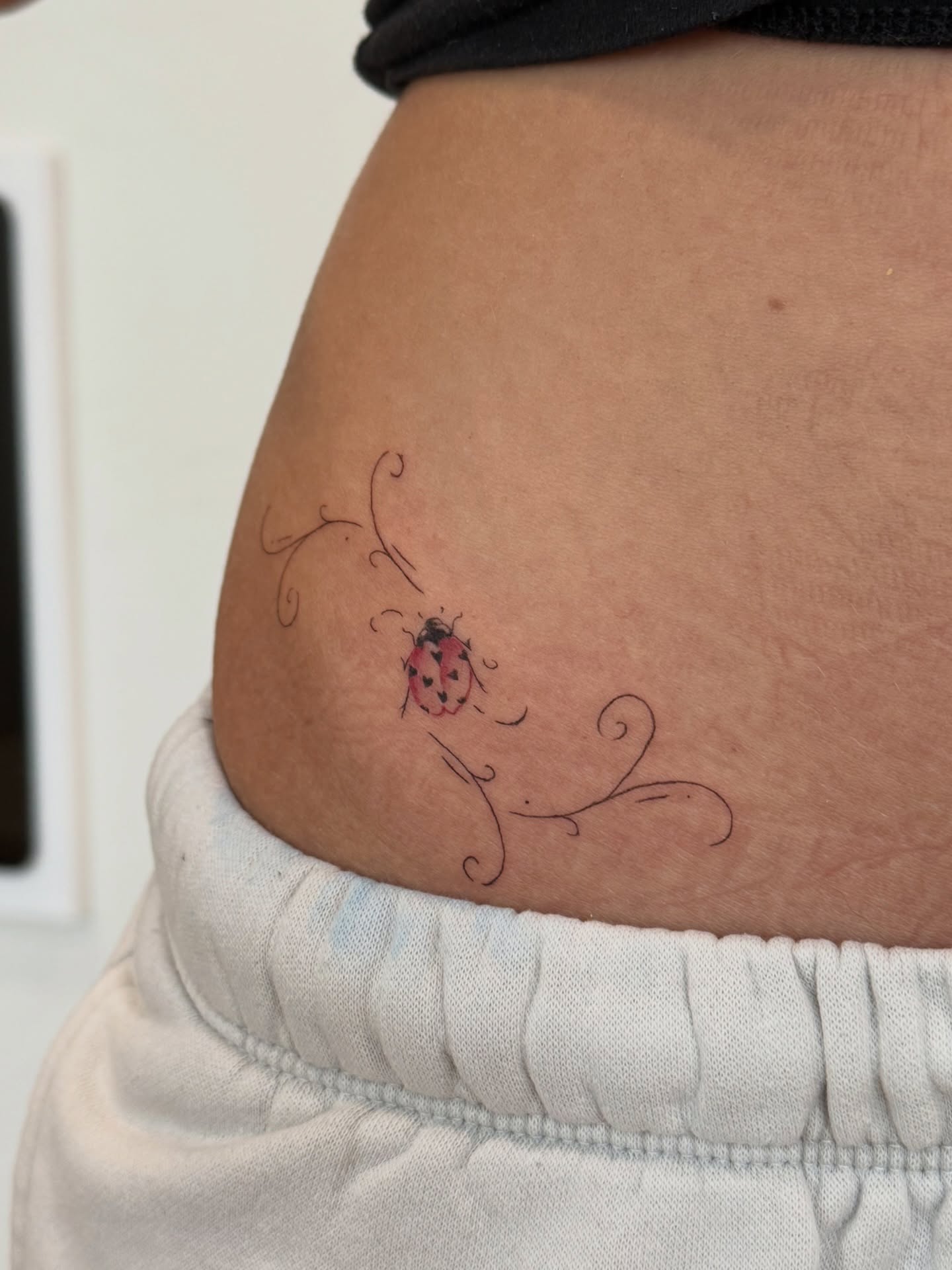 Ladybug fine line tattoo on the thigh by Fine Line Tattoos