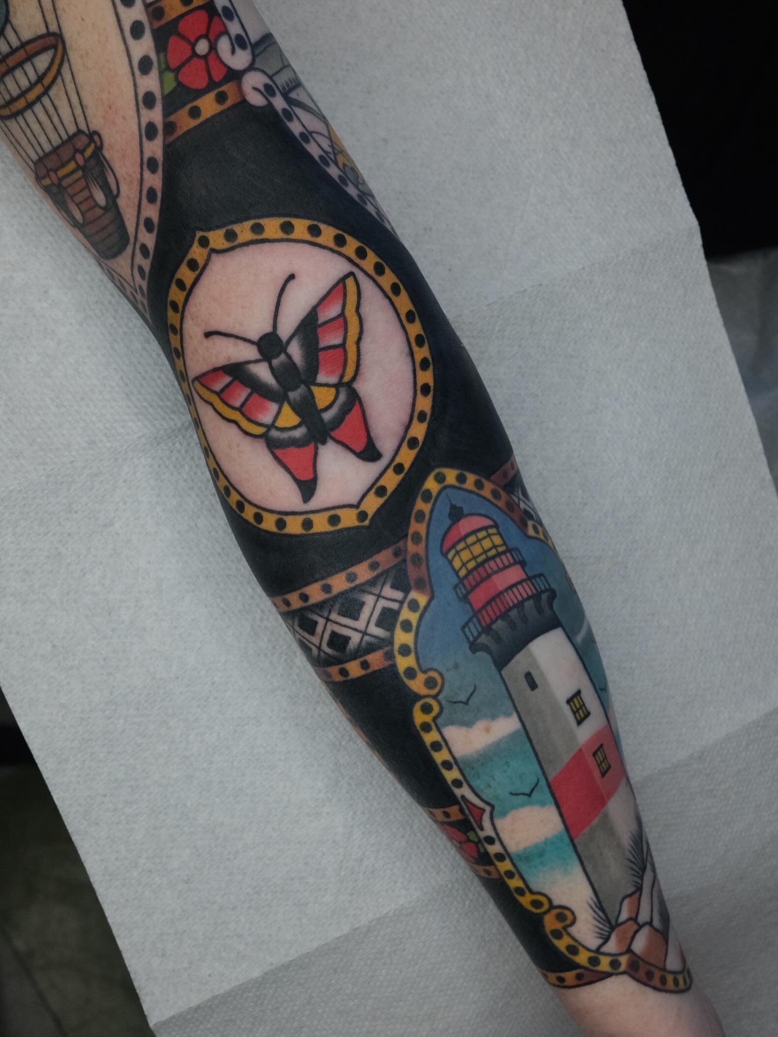 Butterfly and lighthouse American traditional tattoo on the forearm by James Maxwell