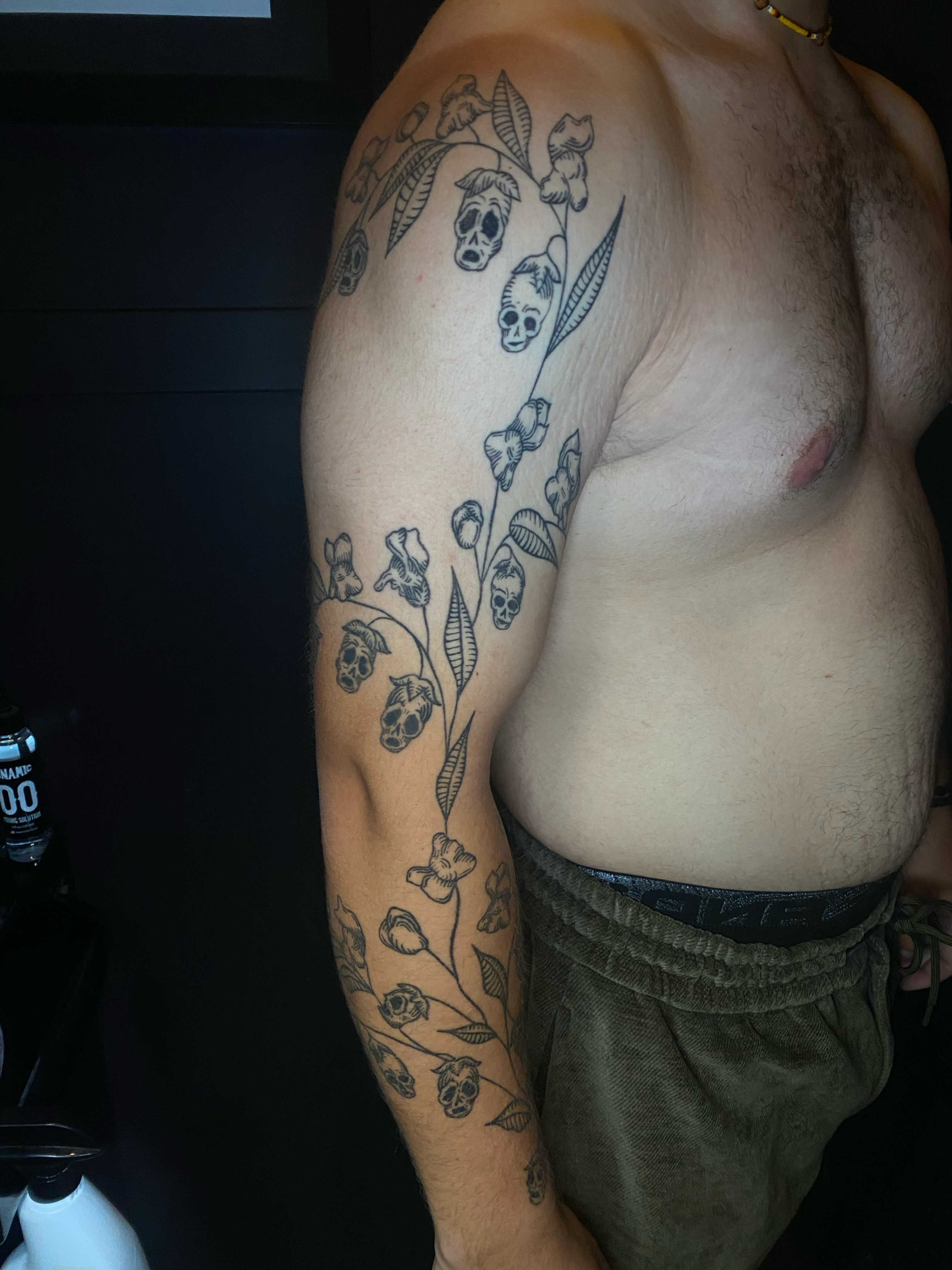 Skulls and flowers black and grey tattoo on the upper arm by Cherry Jane 🍒