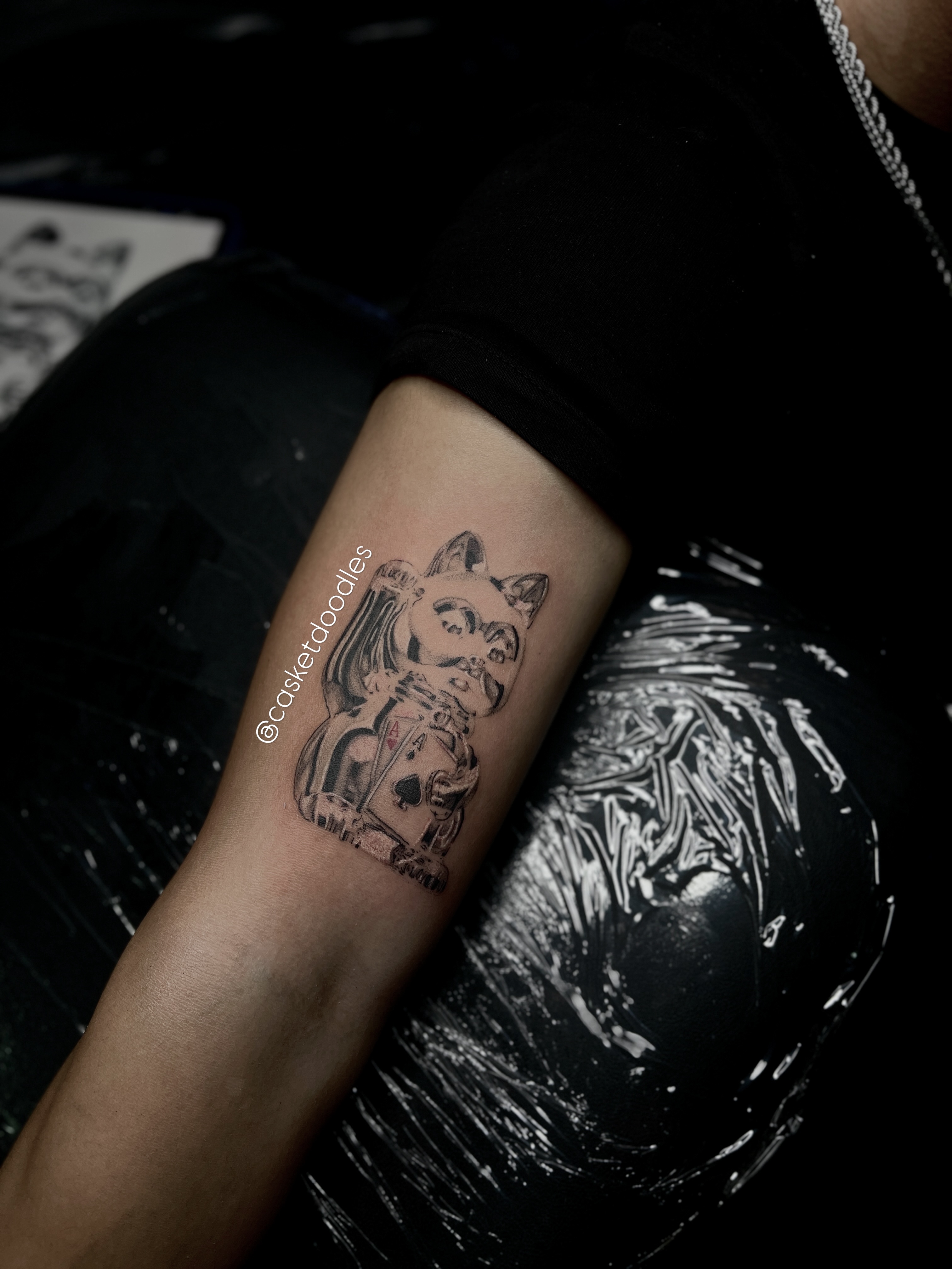 Cat with playing card black and grey tattoo on the forearm by clarissa