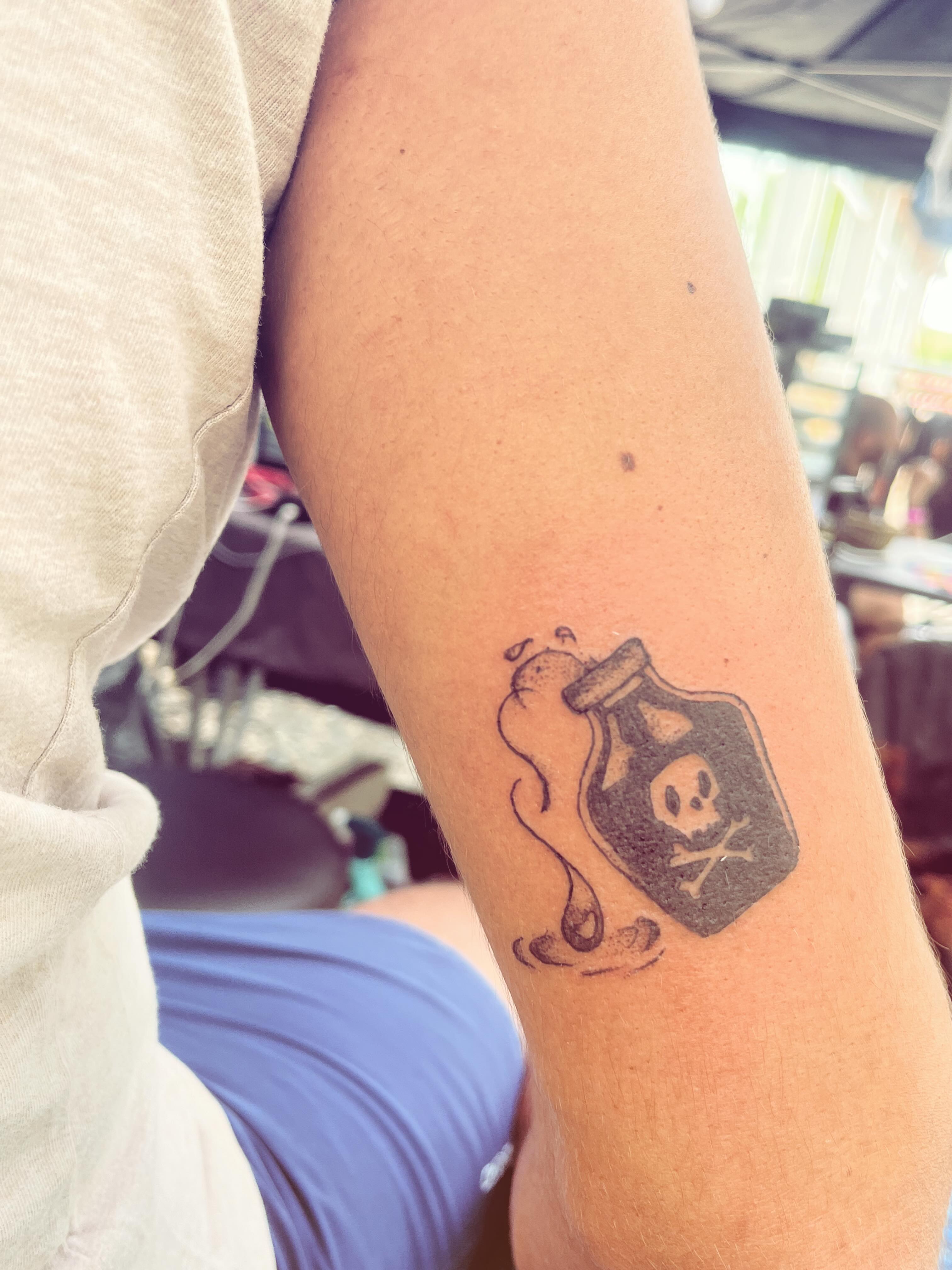 Poison bottle black and grey tattoo on the forearm by La Main Bleue
