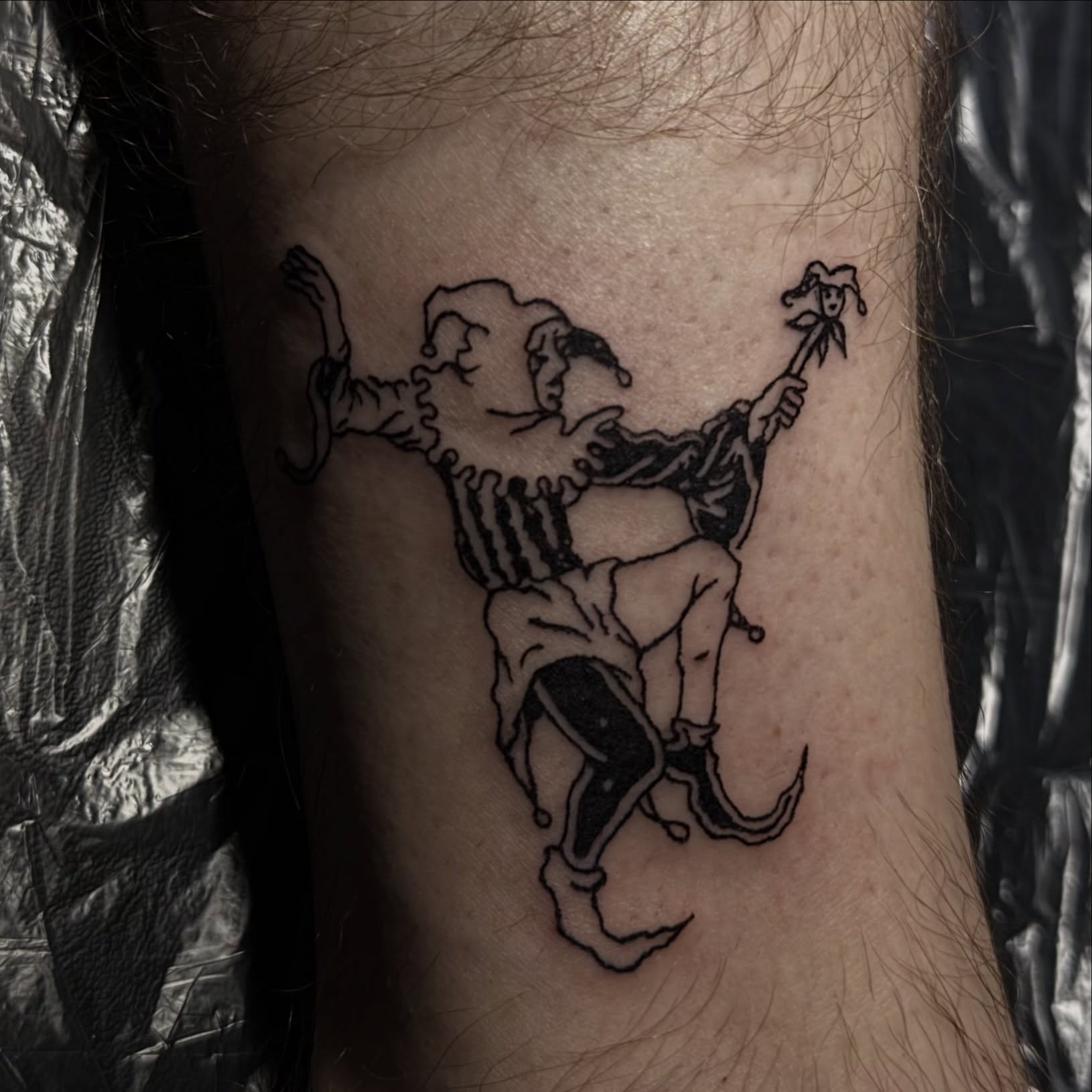 Clown and jester black and grey tattoo on the forearm by Casper Tattoos Toronto