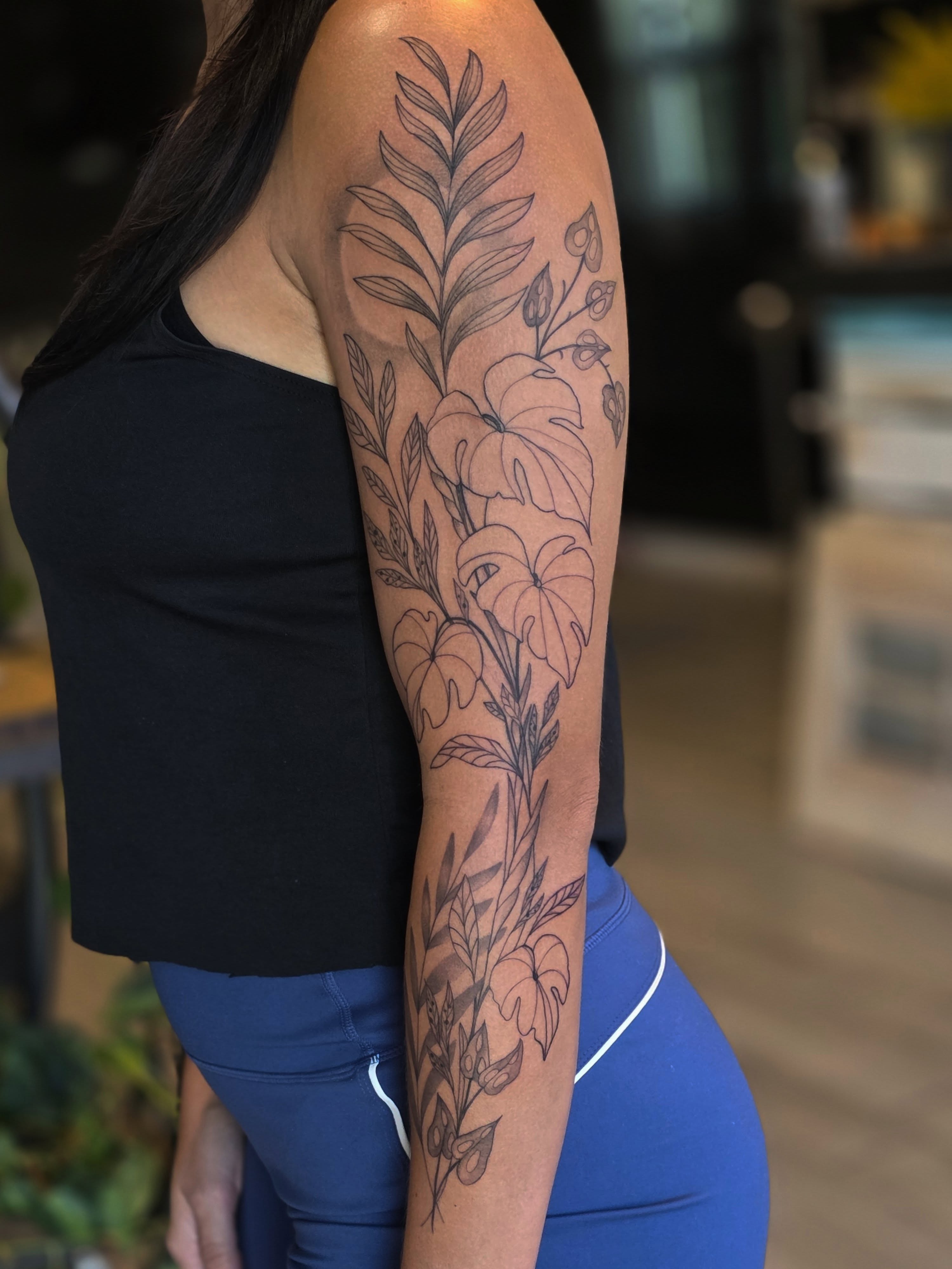 Floral arrangement black and grey tattoo on the upper arm by Casey Jo
