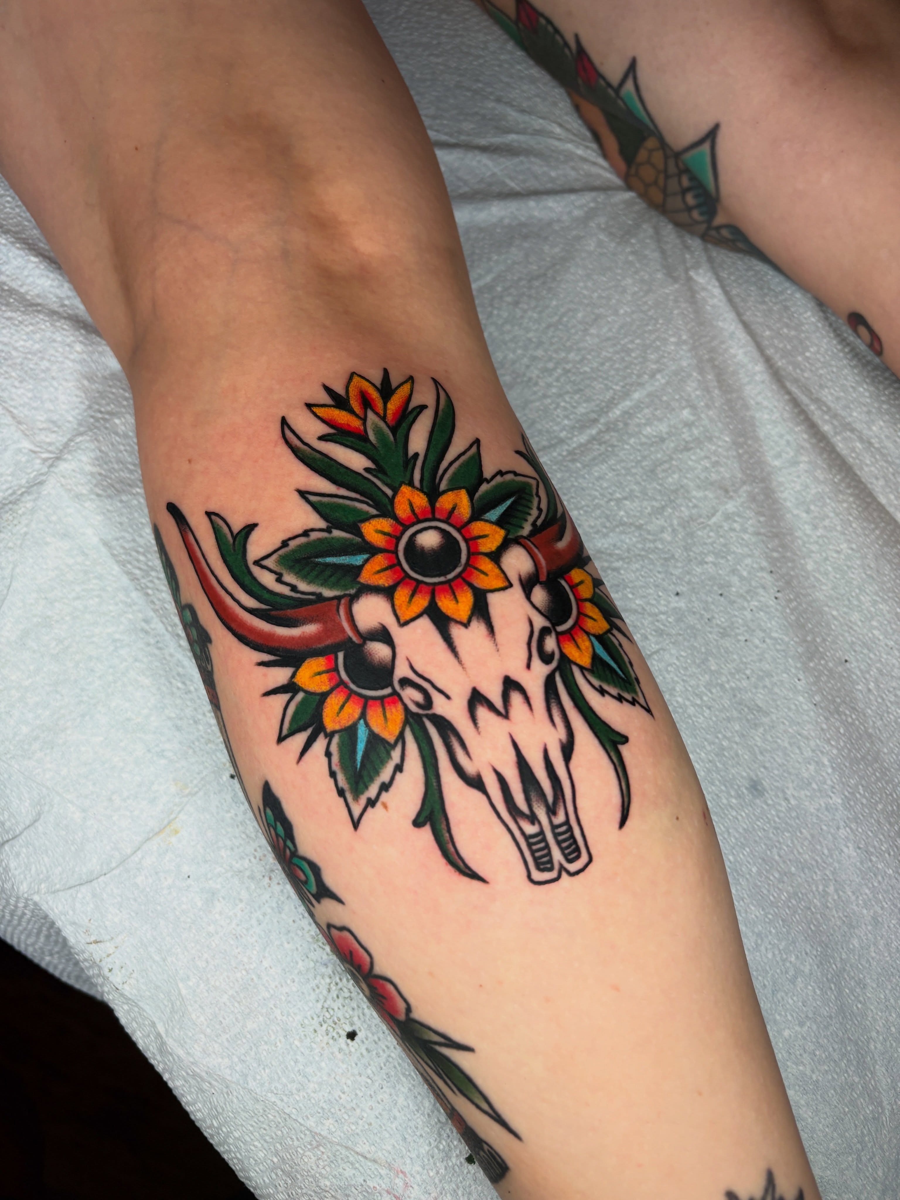 Cow skull with flowers American traditional tattoo on the forearm by Max Klapp, Austin, Texas