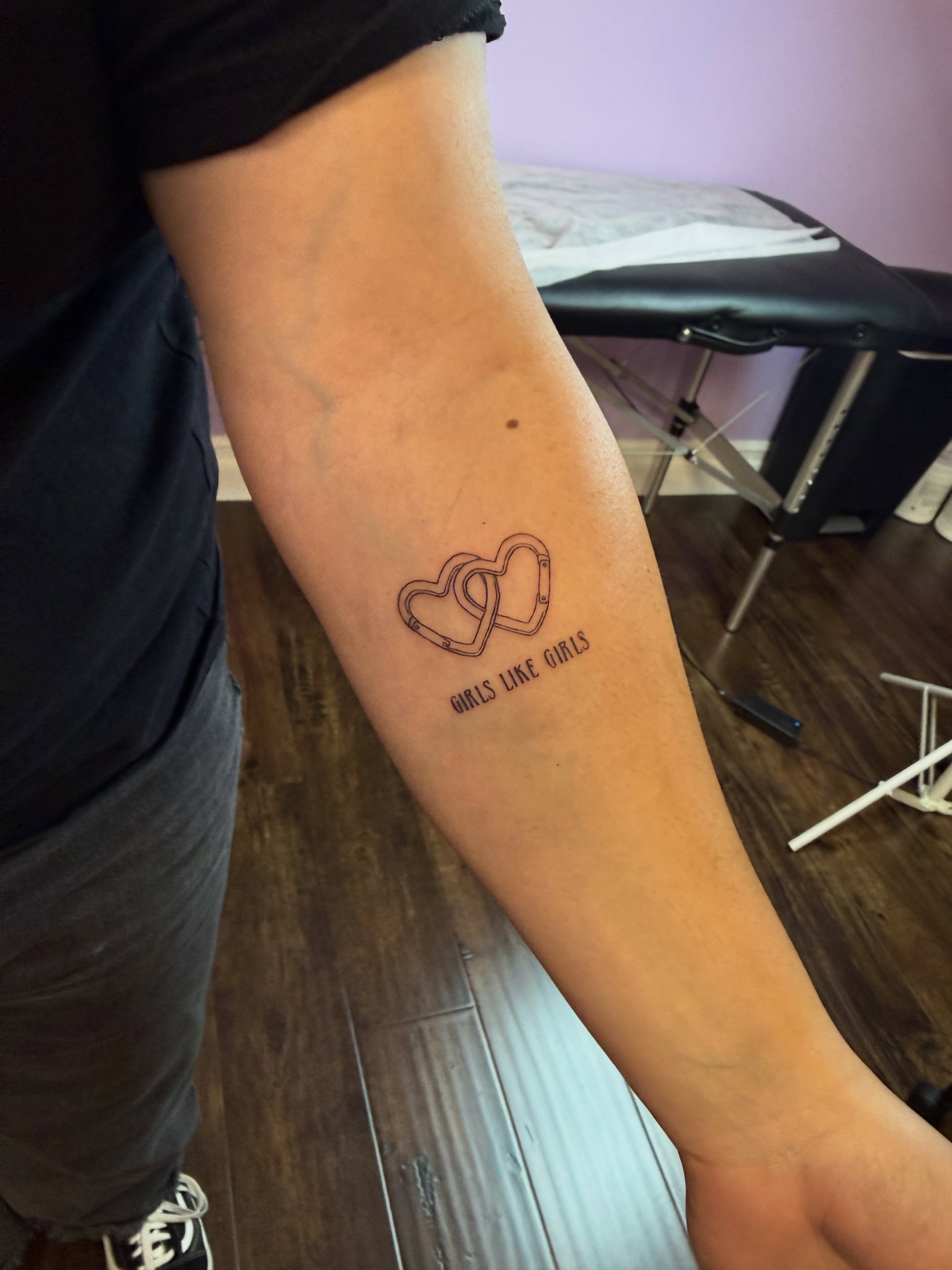 Interlocking hearts fine line tattoo on the forearm by Jay