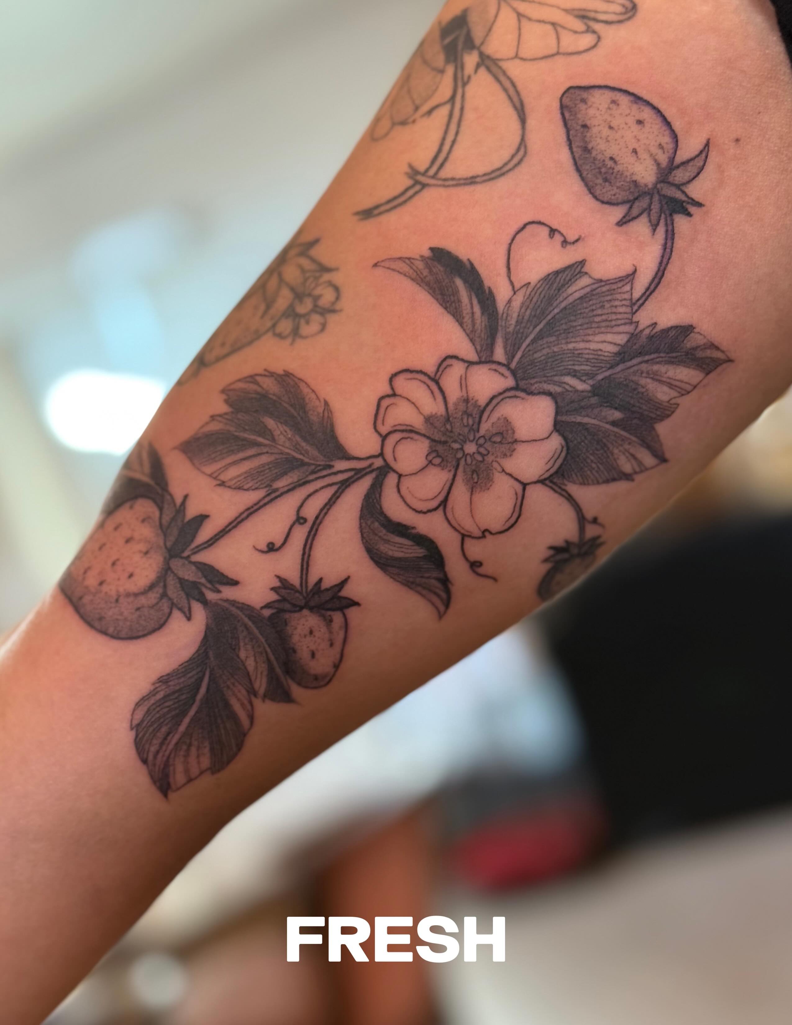 Strawberries and flowers black and grey tattoo on the forearm by Julianna