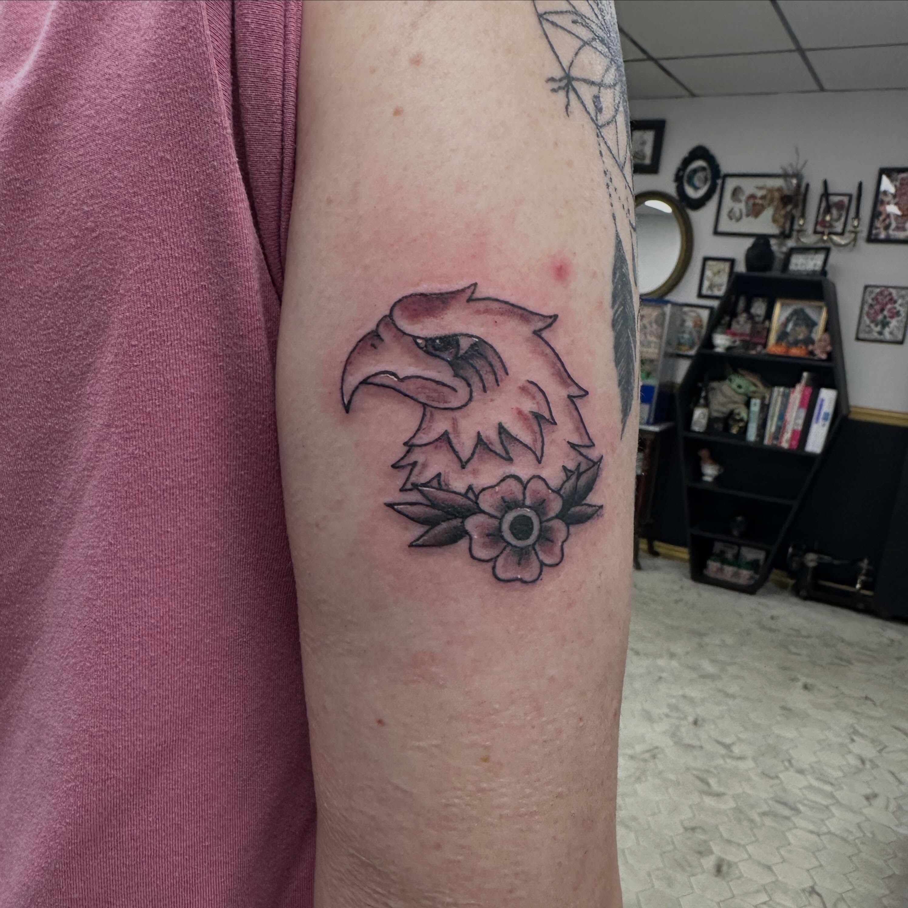 Eagle head with flowers neo-traditional tattoo on the forearm by Nicki Hoverson