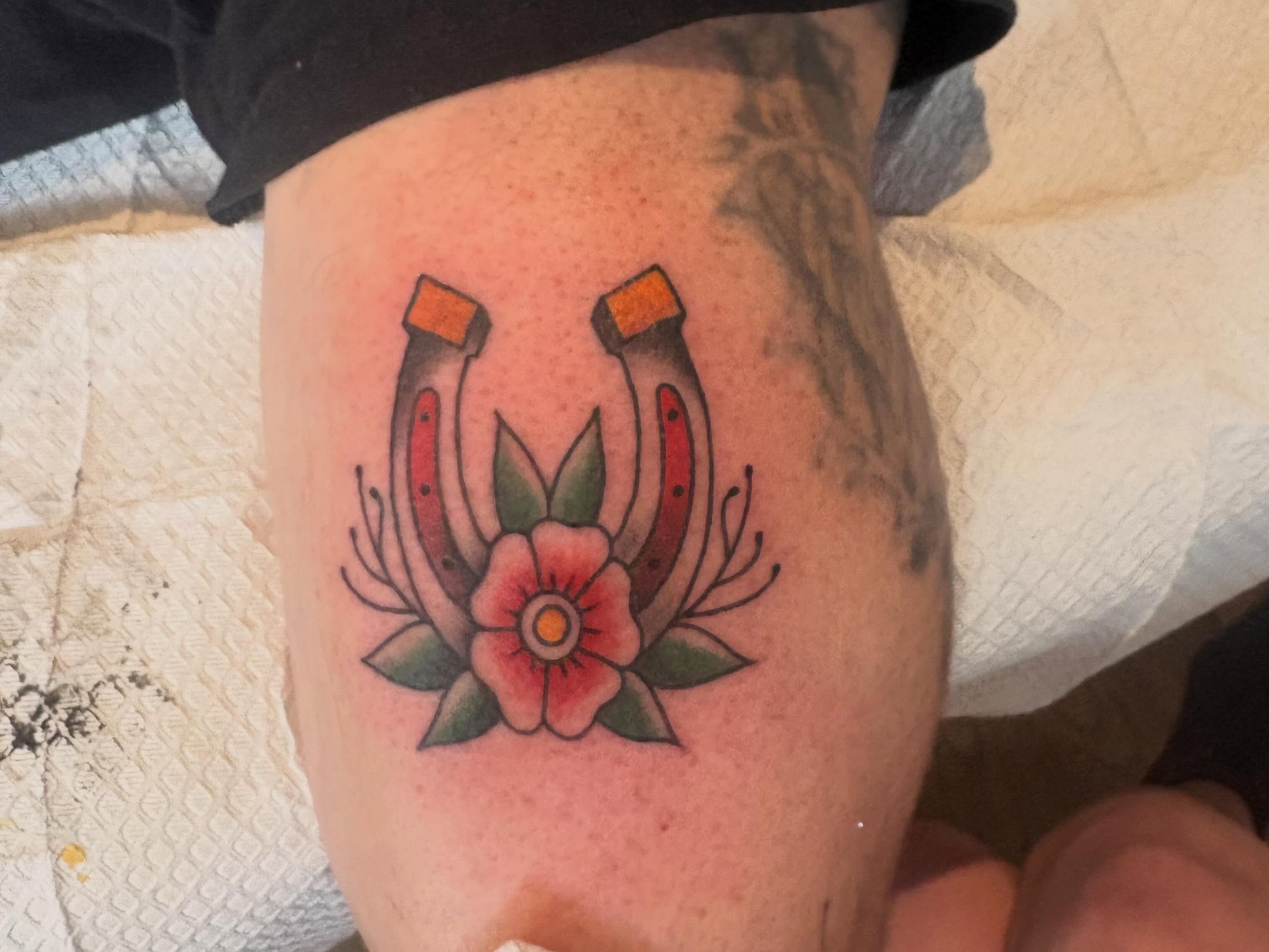 Horseshoes and flower American traditional tattoo on the thigh by Adriana Wimler