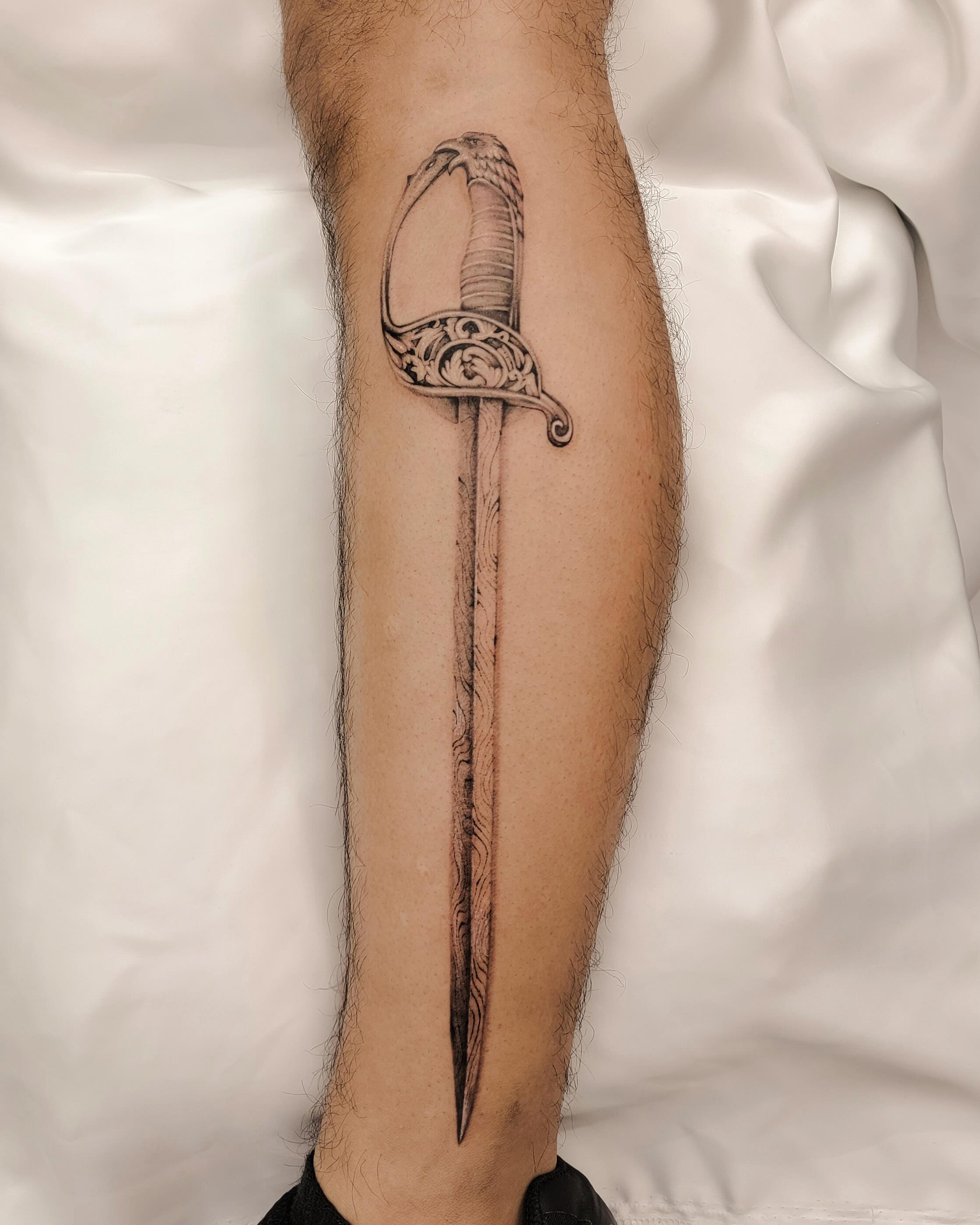 Sword black and grey tattoo on the forearm by Koko
