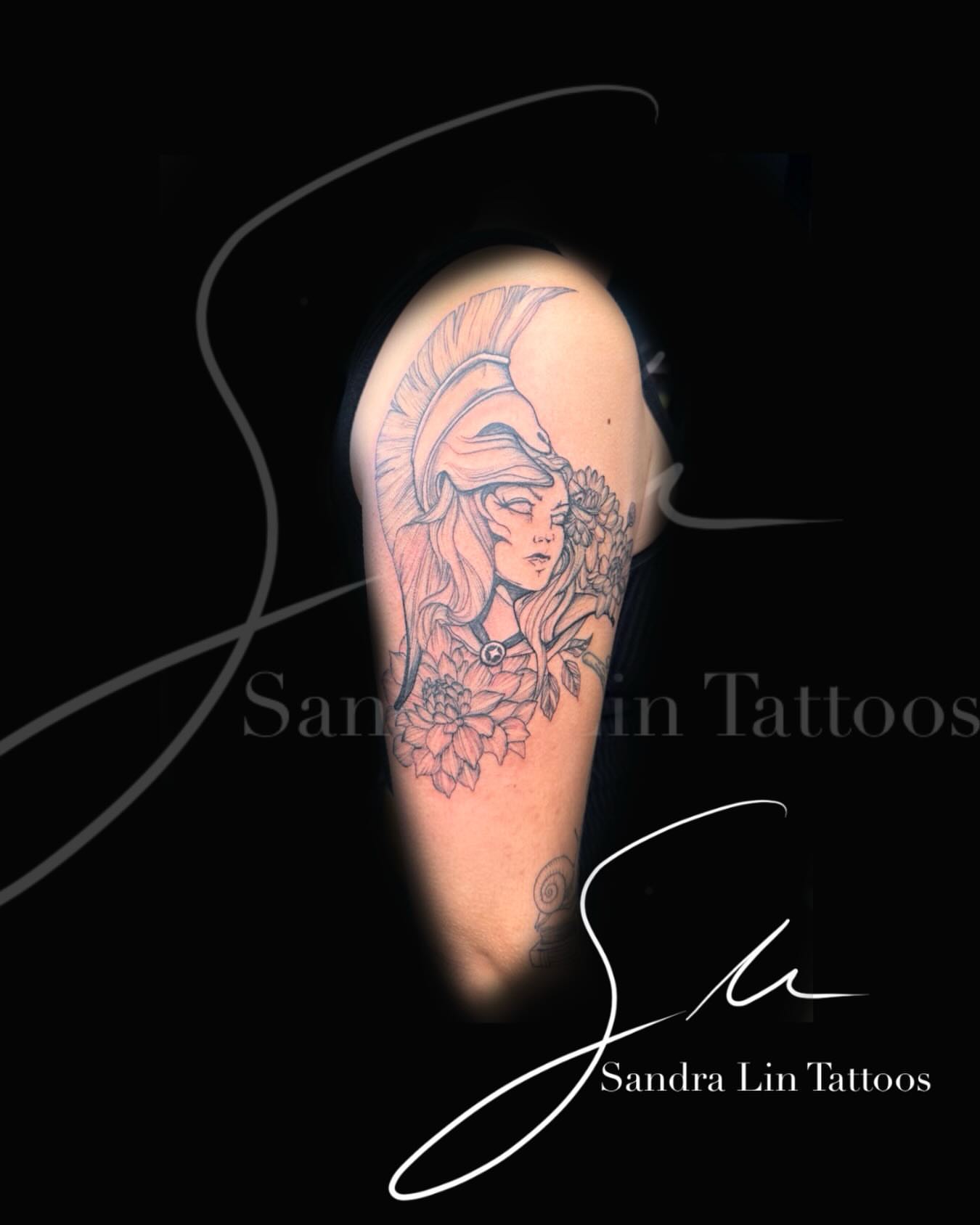Woman with helmet black and grey tattoo on the shoulder by Sandra Lin Cue