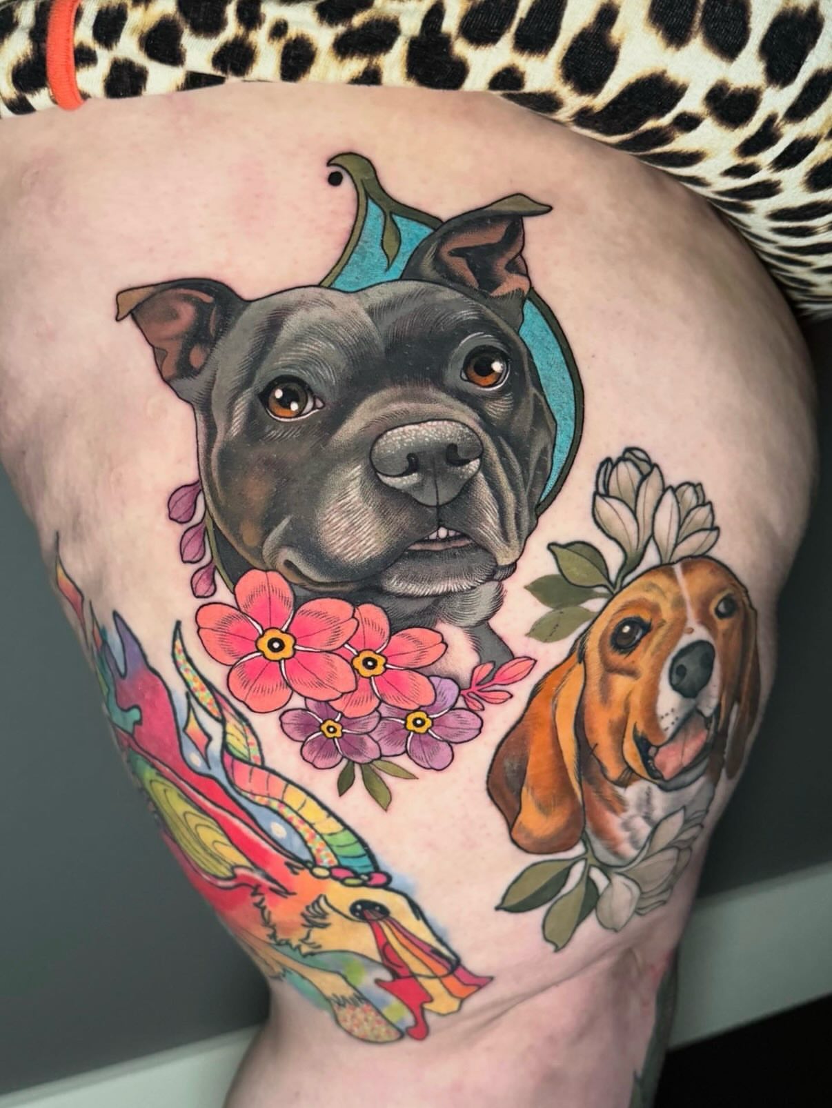 Dogs and flowers realism tattoo on the thigh by Connie Fiorino - Tattoo Artist